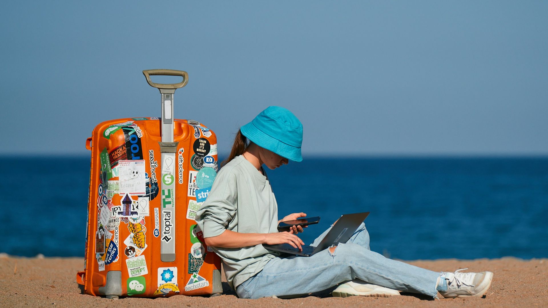 a person sitting on the beach with a suitcase