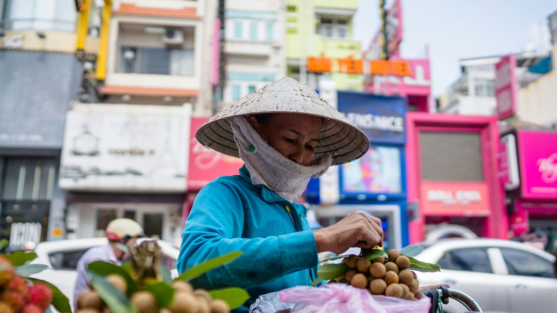 woman in blue long sleeve shirt and brown straw hat holding red fruit