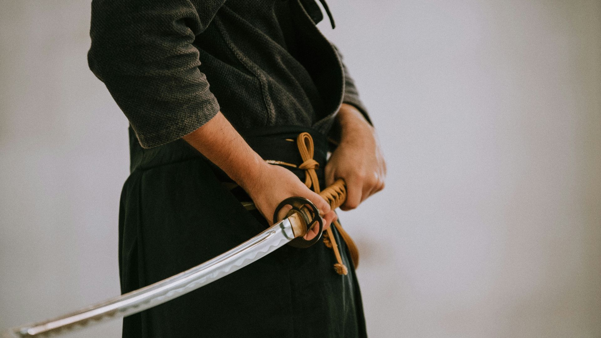 person in black long sleeve shirt and black skirt holding white leather belt