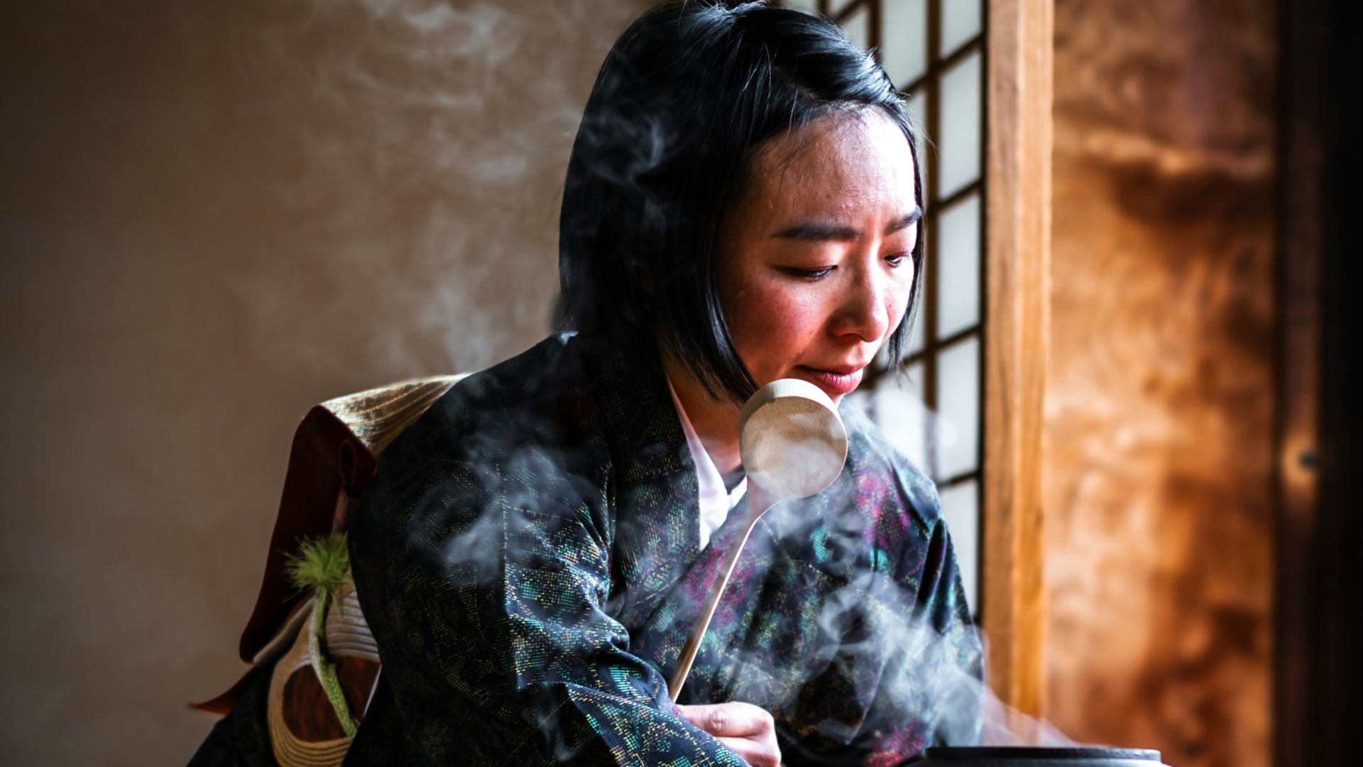 Woman prepares traditional tea in a serene setting.