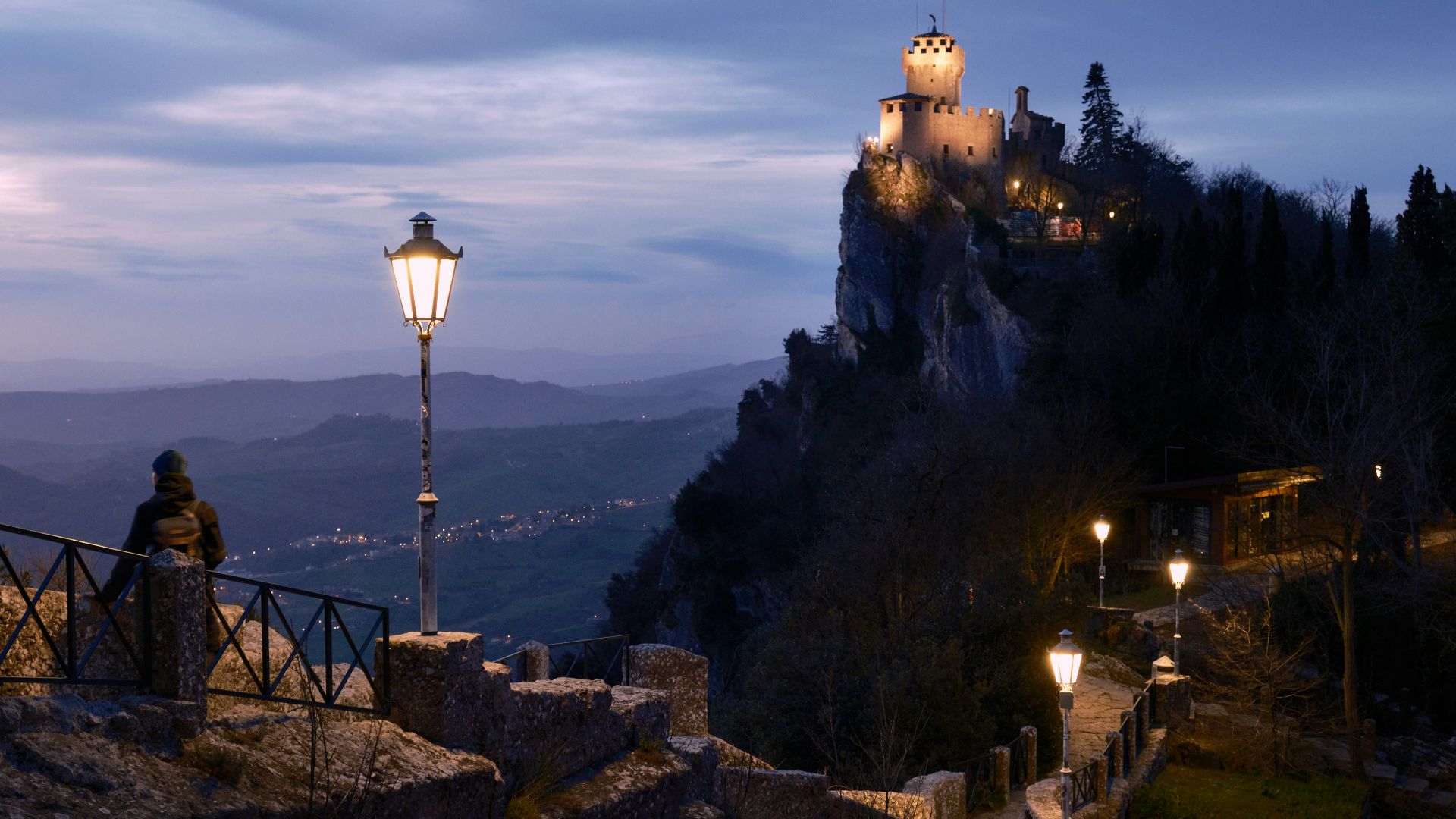 a person standing on a bridge looking at a castle