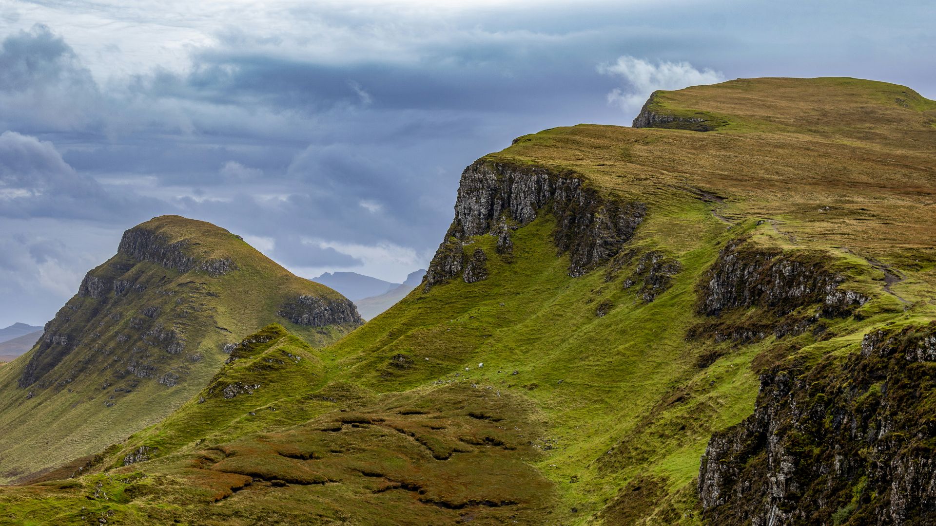 a grassy mountain side with a few clouds in the sky