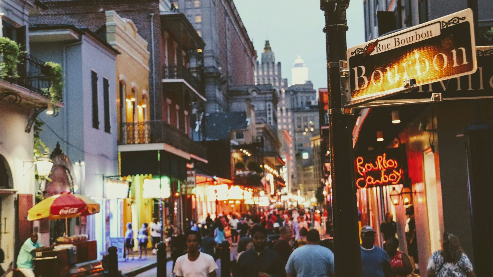 a group of people walking down a street next to tall buildings