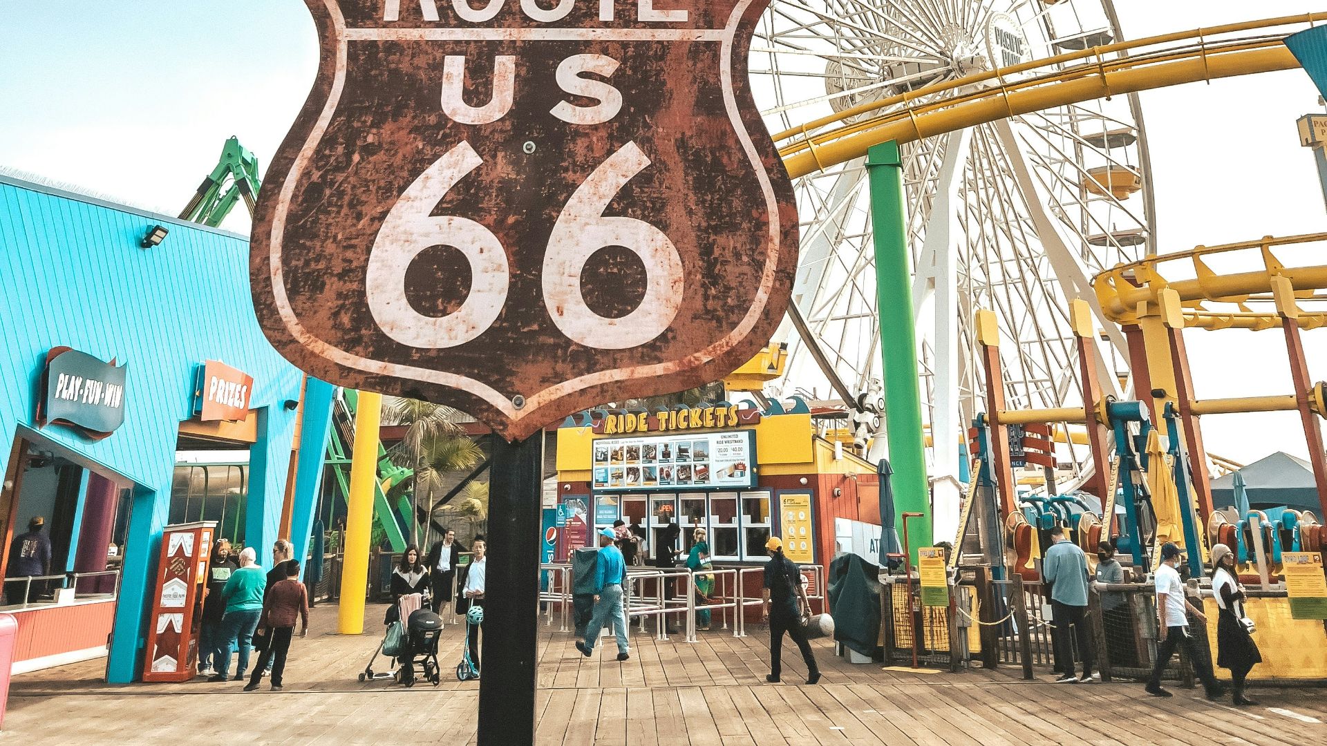 a sign that says route us 66 with a ferris wheel in the background