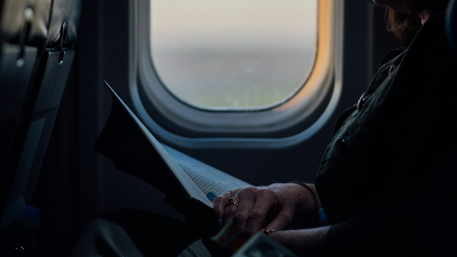 woman sitting and reading book on airliner