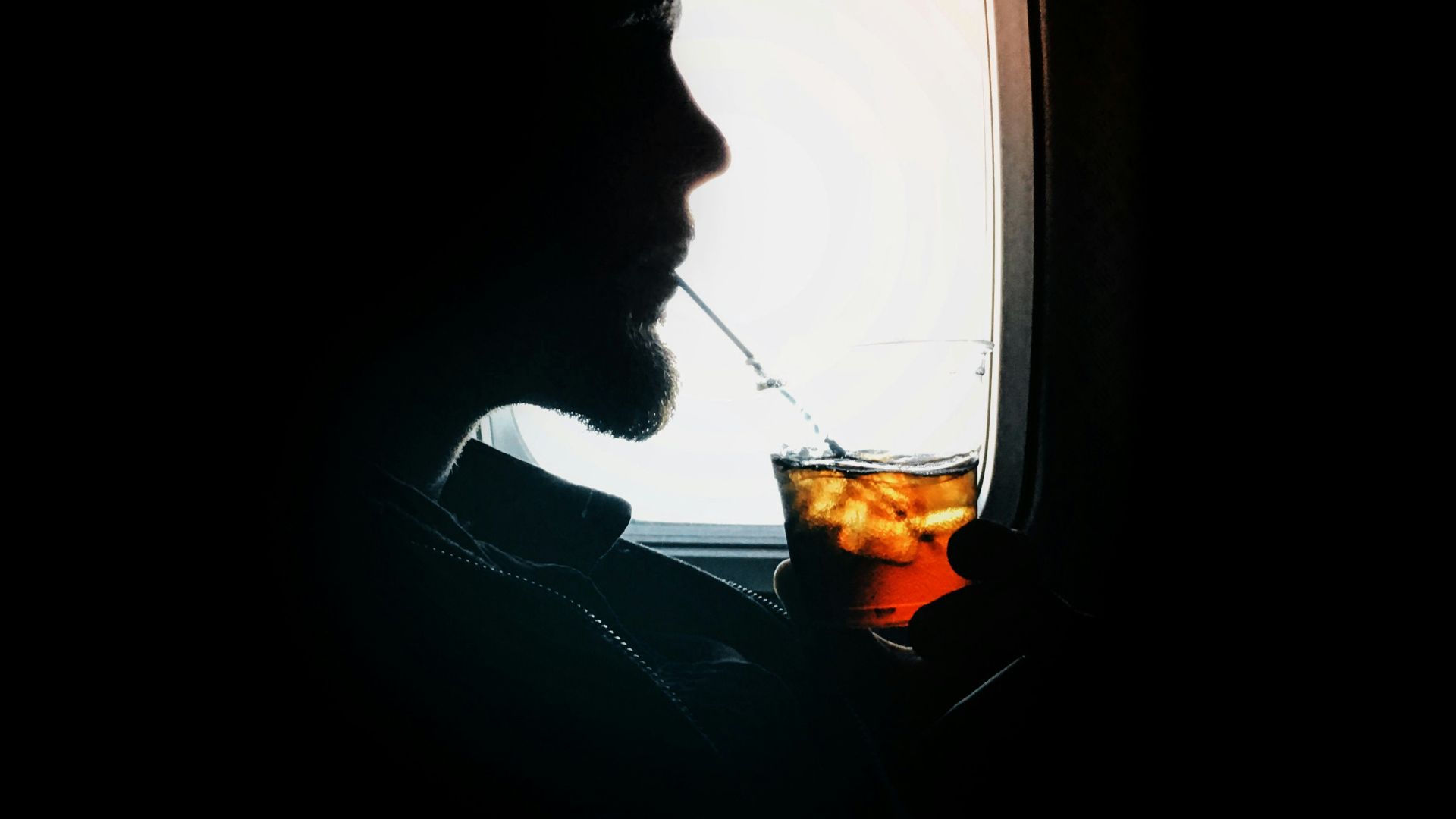 man sipping drink beside window