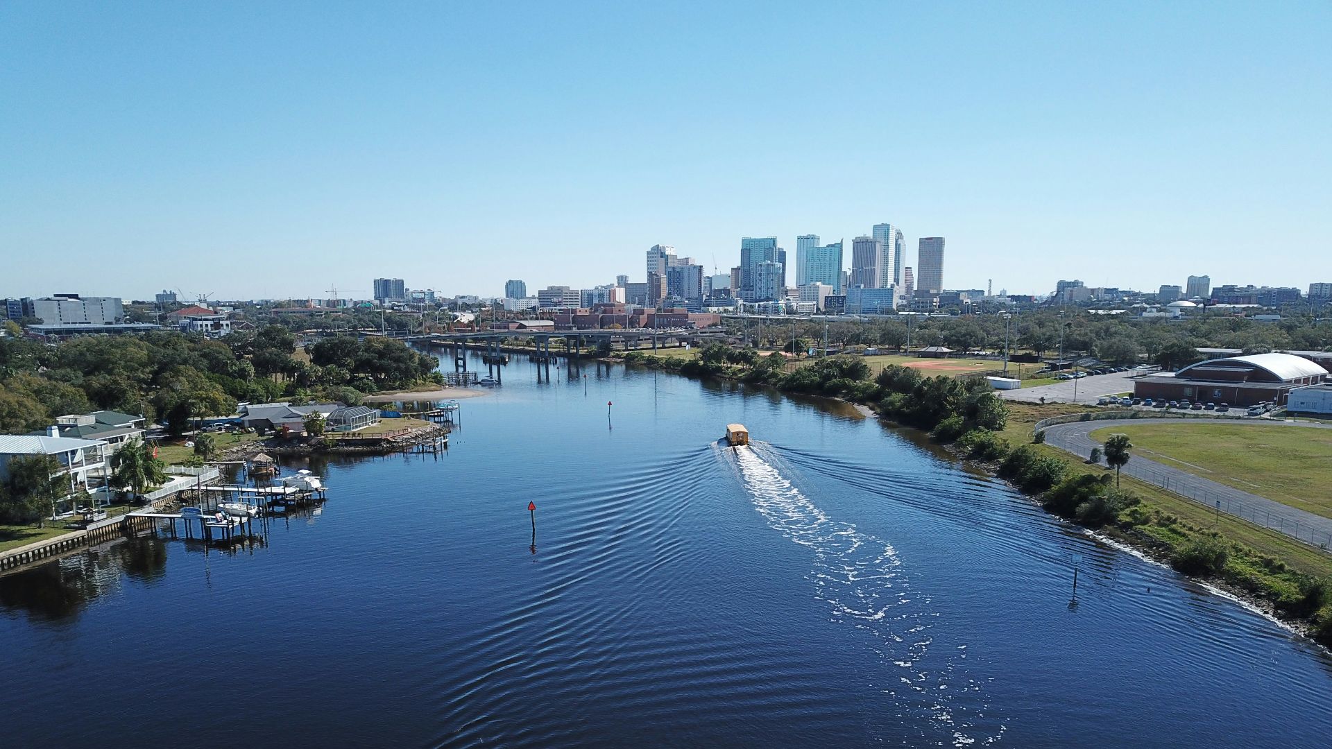 white boat on body of water near city buildings during daytime