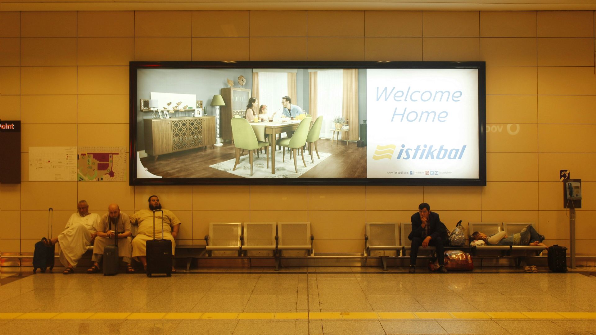 a group of people sitting on a bench in front of a large screen