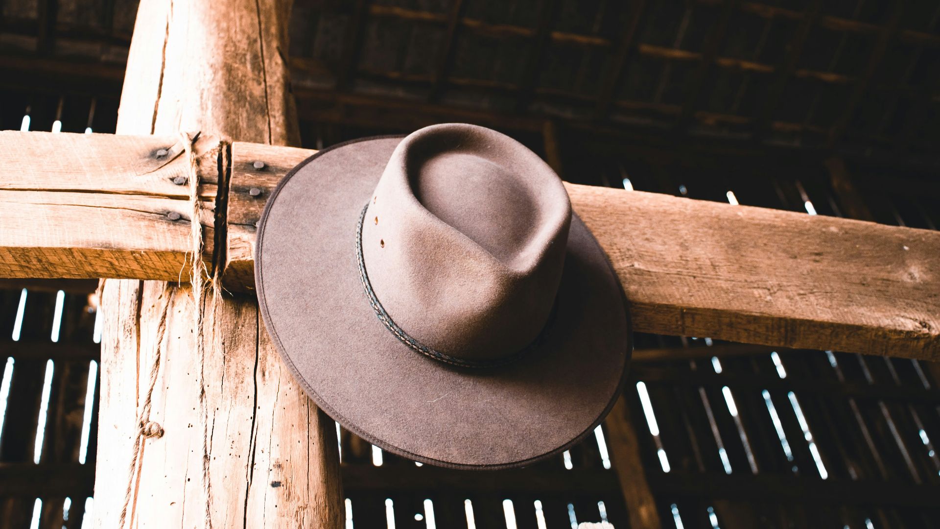 a brown hat is hanging on a wooden pole