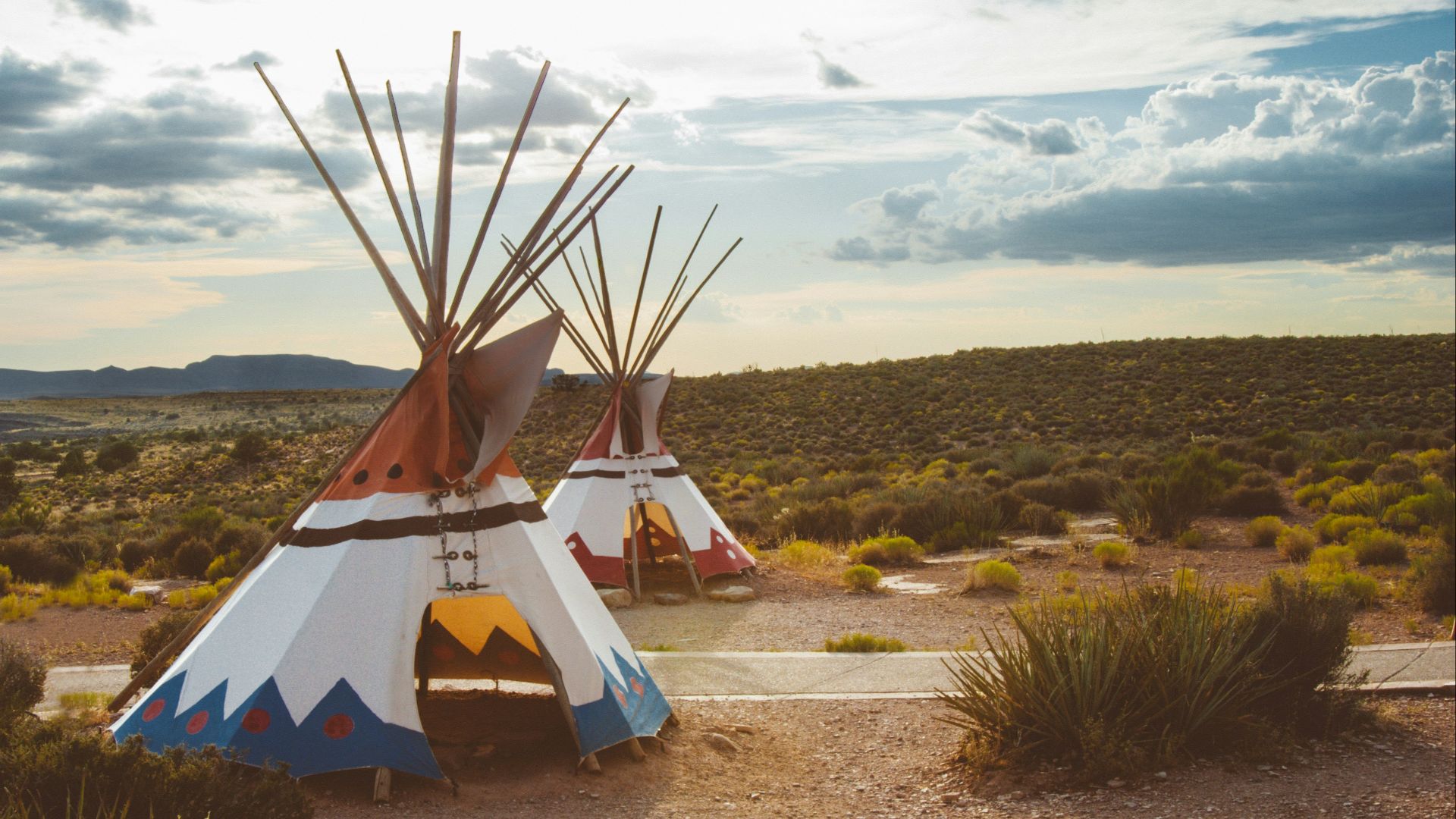 two white-blue-and-red teepee tents surrounded by green plants
