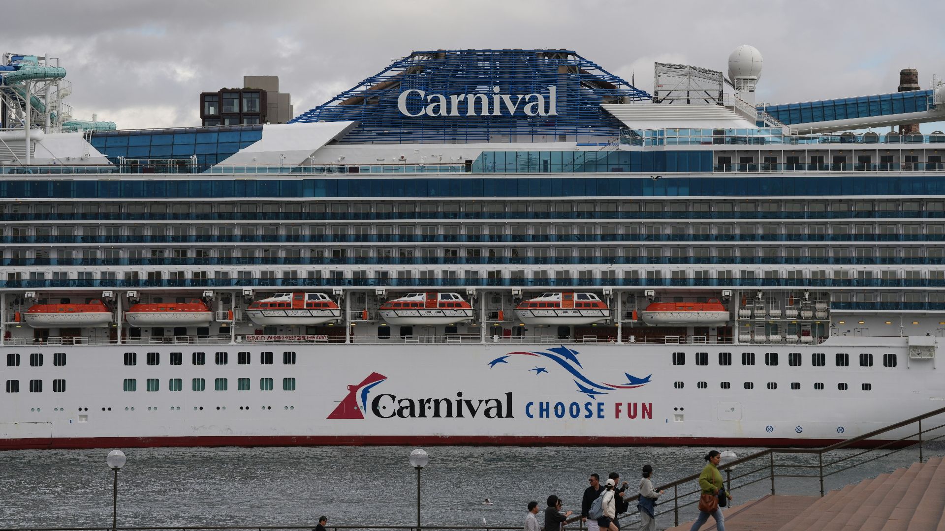 A carnival cruise ship is docked at a pier.