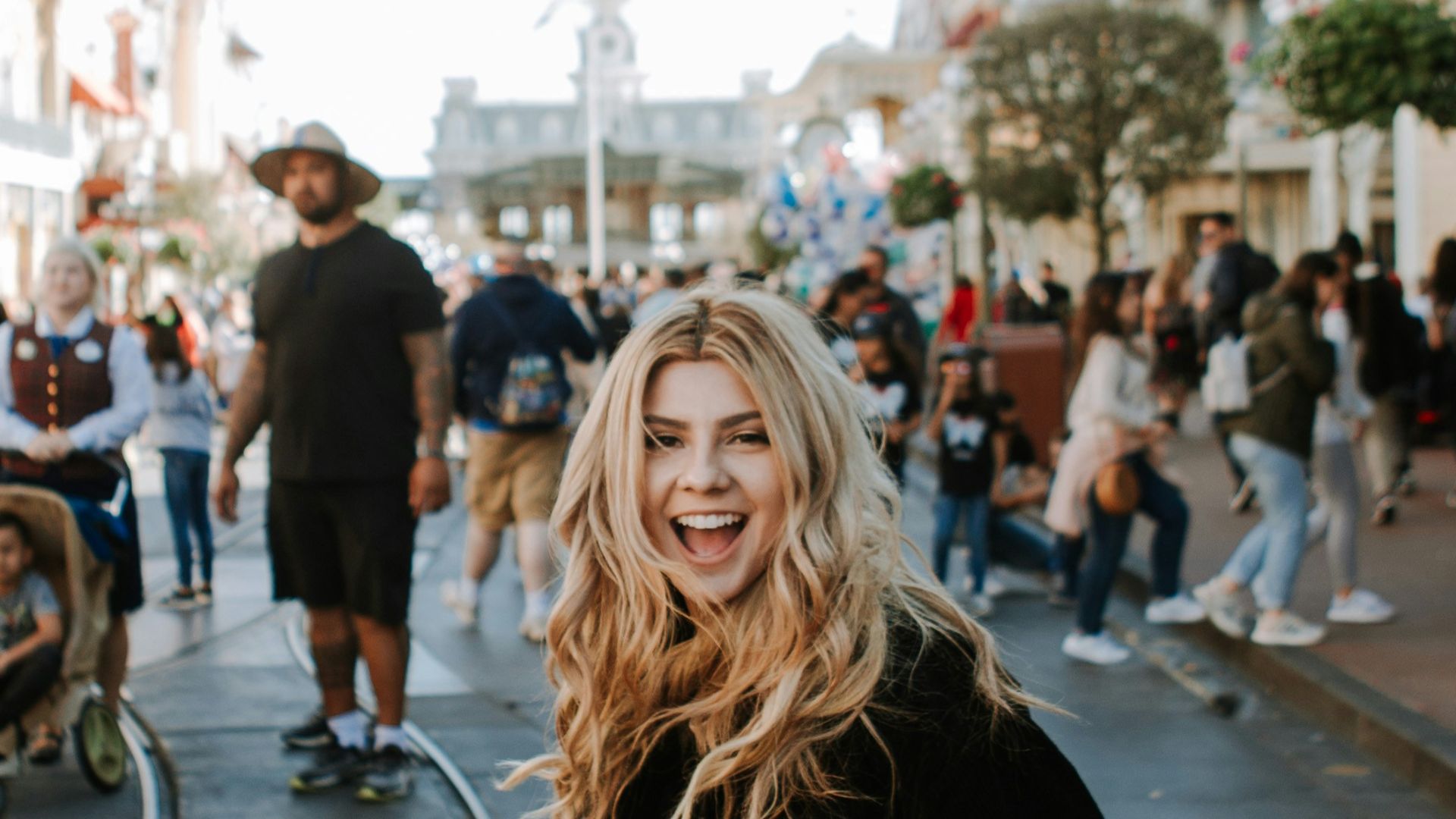 woman in black jacket and brown pants standing on sidewalk during daytime