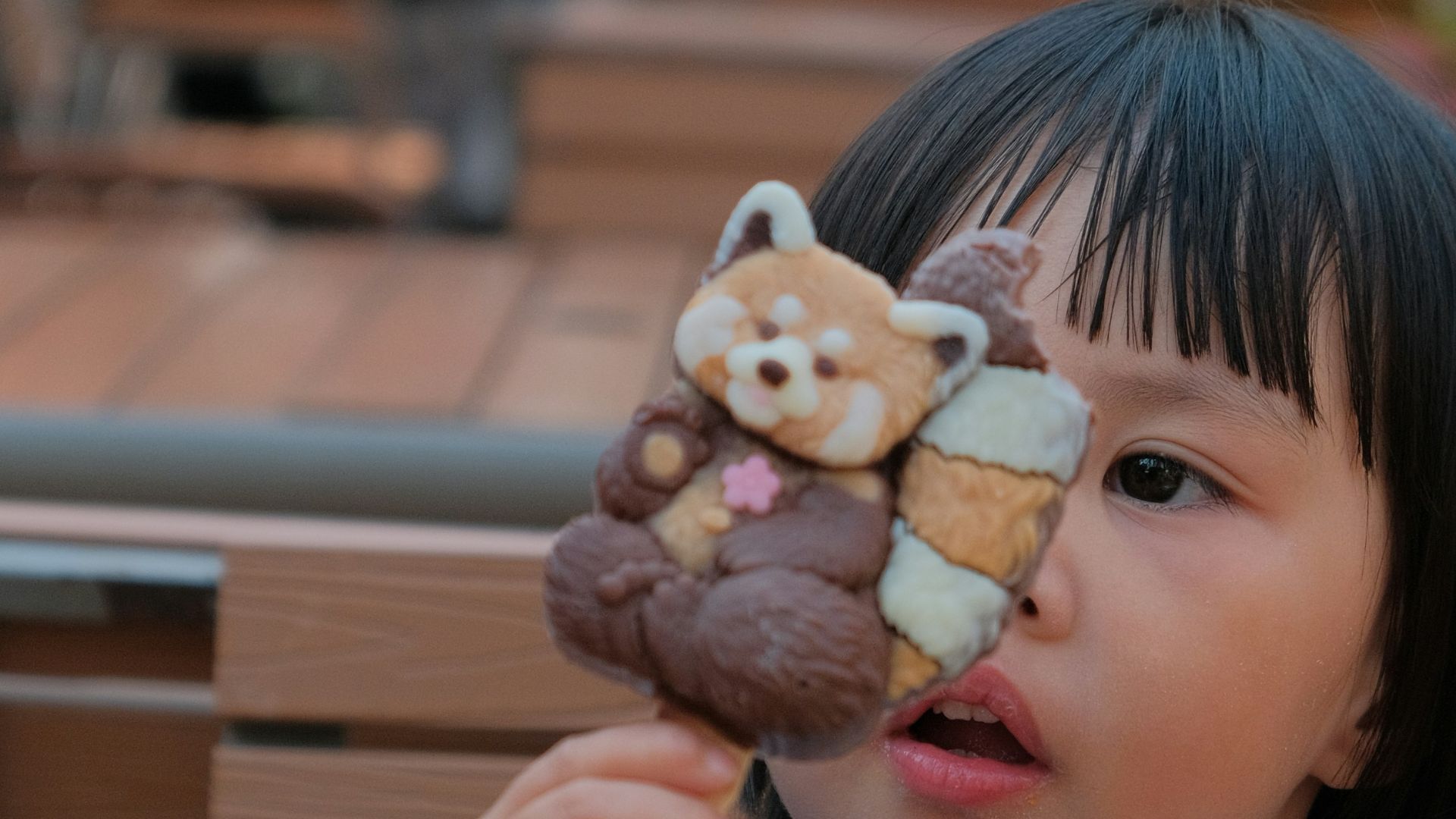 A child holds a red panda ice cream bar.