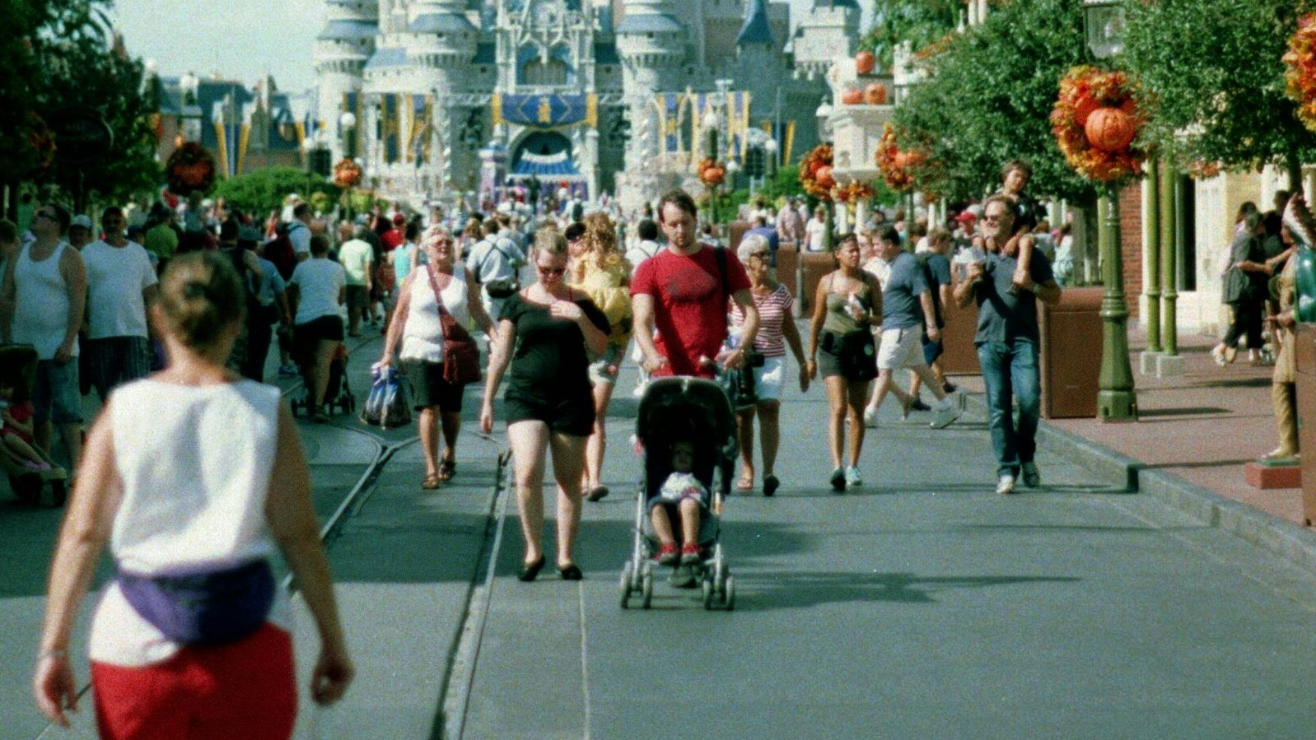 A group of people walking down a street in front of a castle