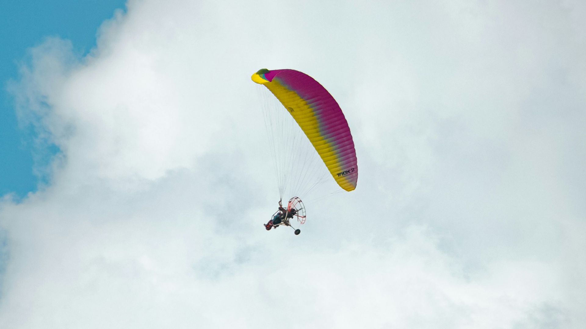 a person is parasailing in the sky on a cloudy day