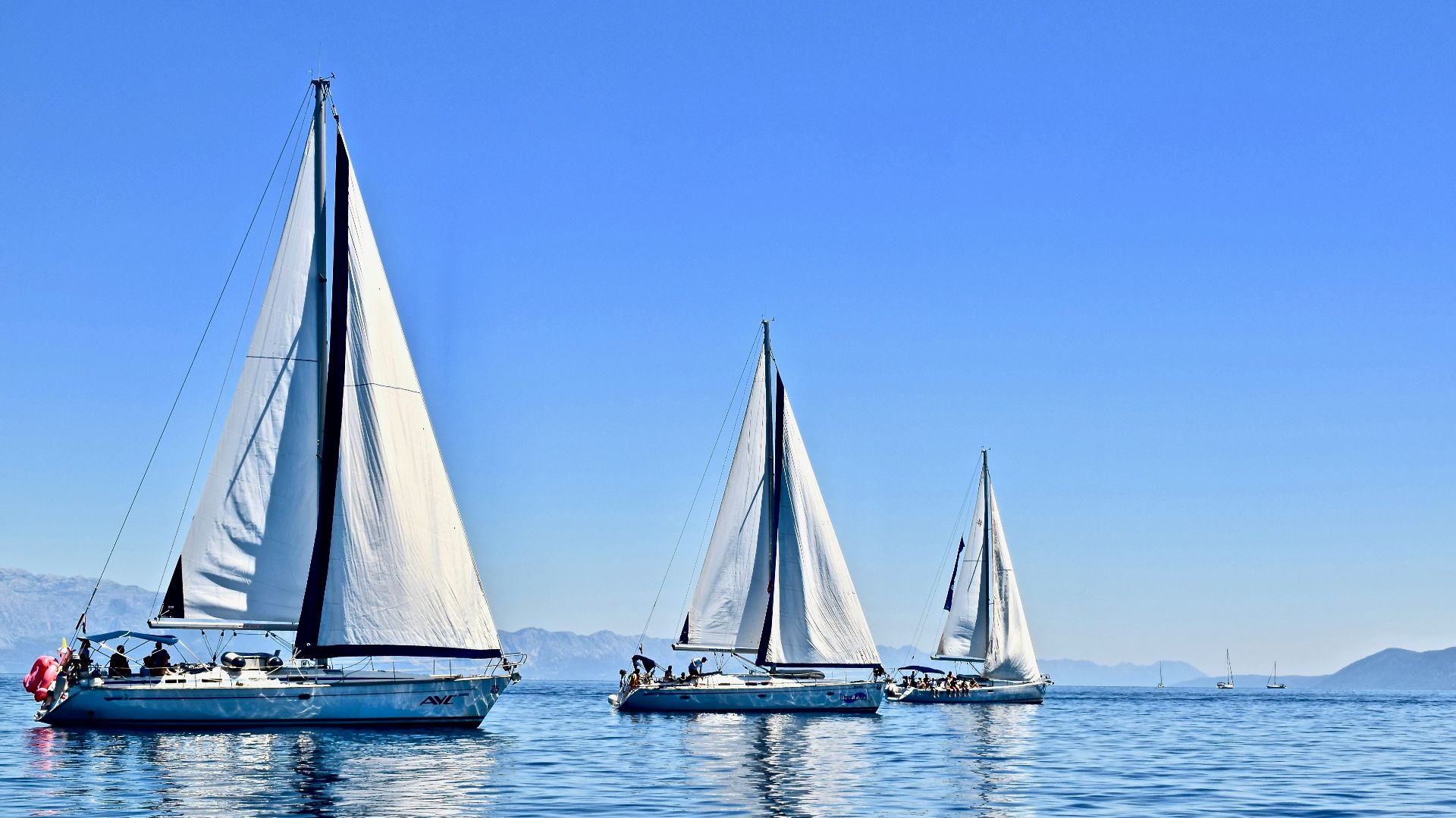 three sail boats on water during daytime