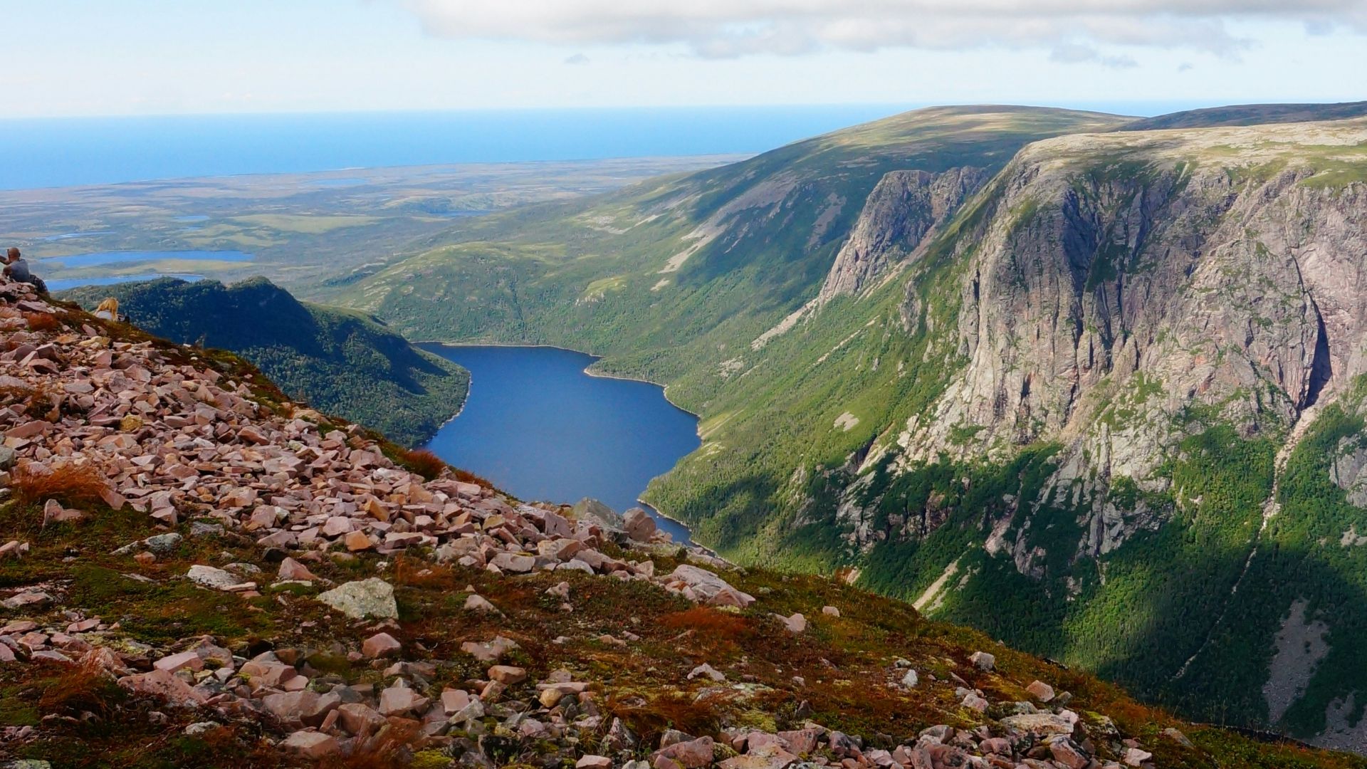 body of water in between of mountains under cloudy sky