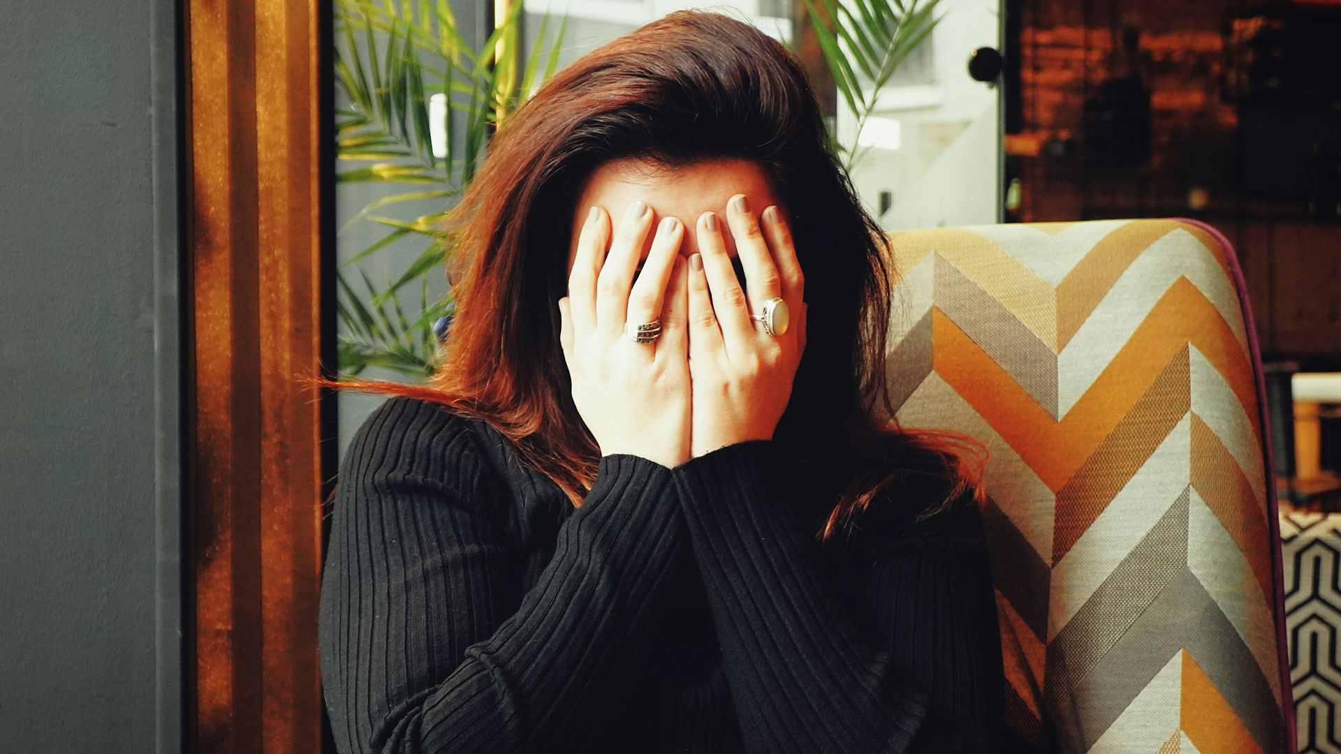 woman in black long sleeve shirt covering her face