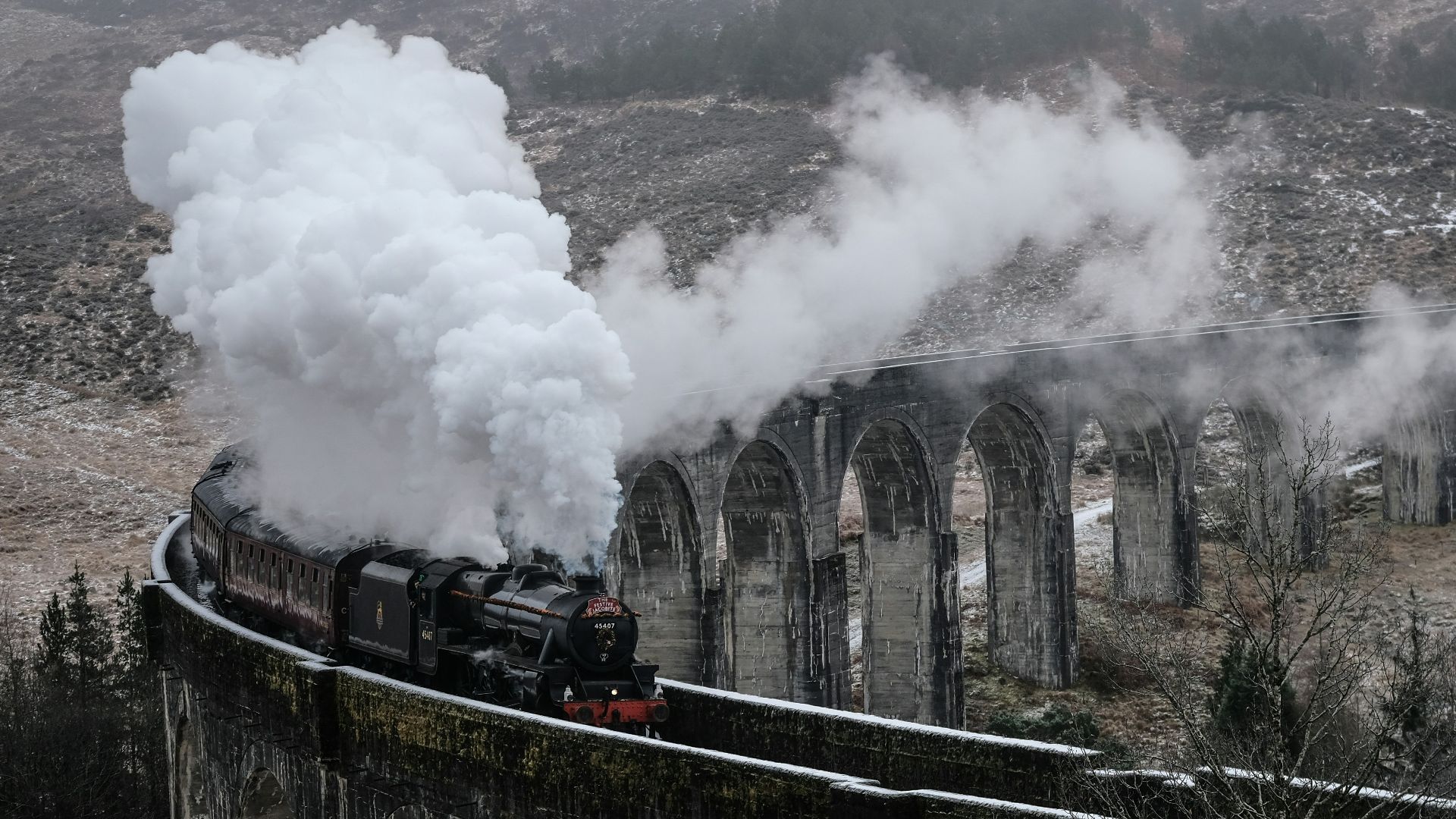 black steam train emitting smoke on concrete railway during daytime