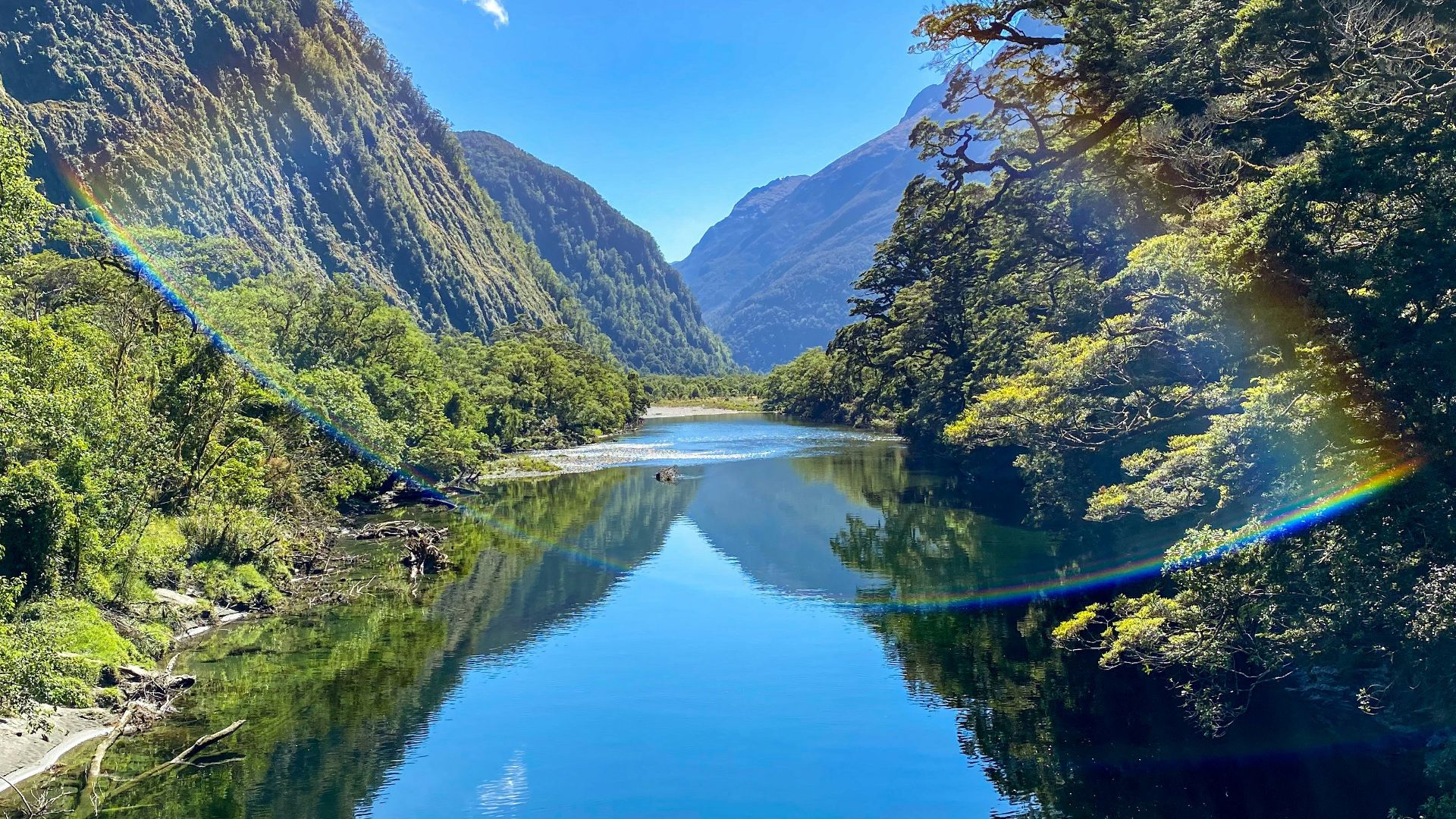 green and brown mountains beside river under blue sky during daytime