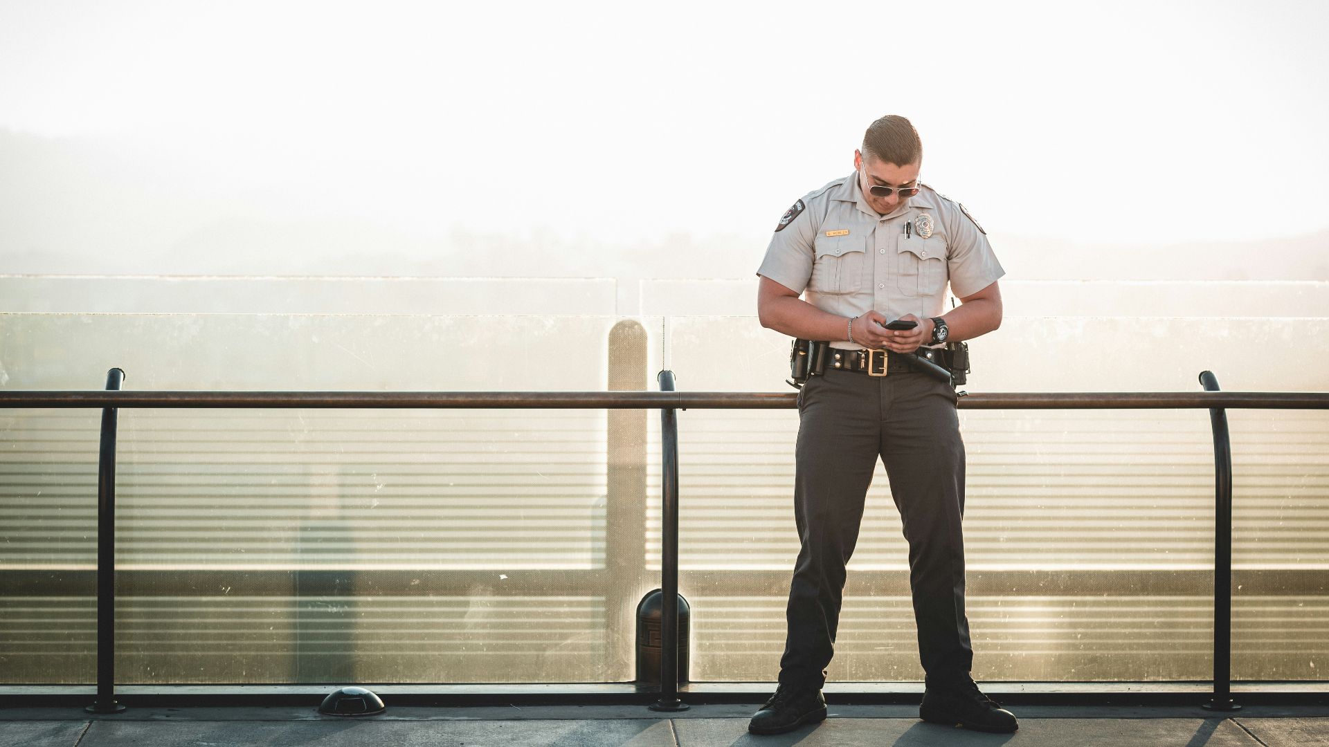 cop leaning on metal rail during a sunny day