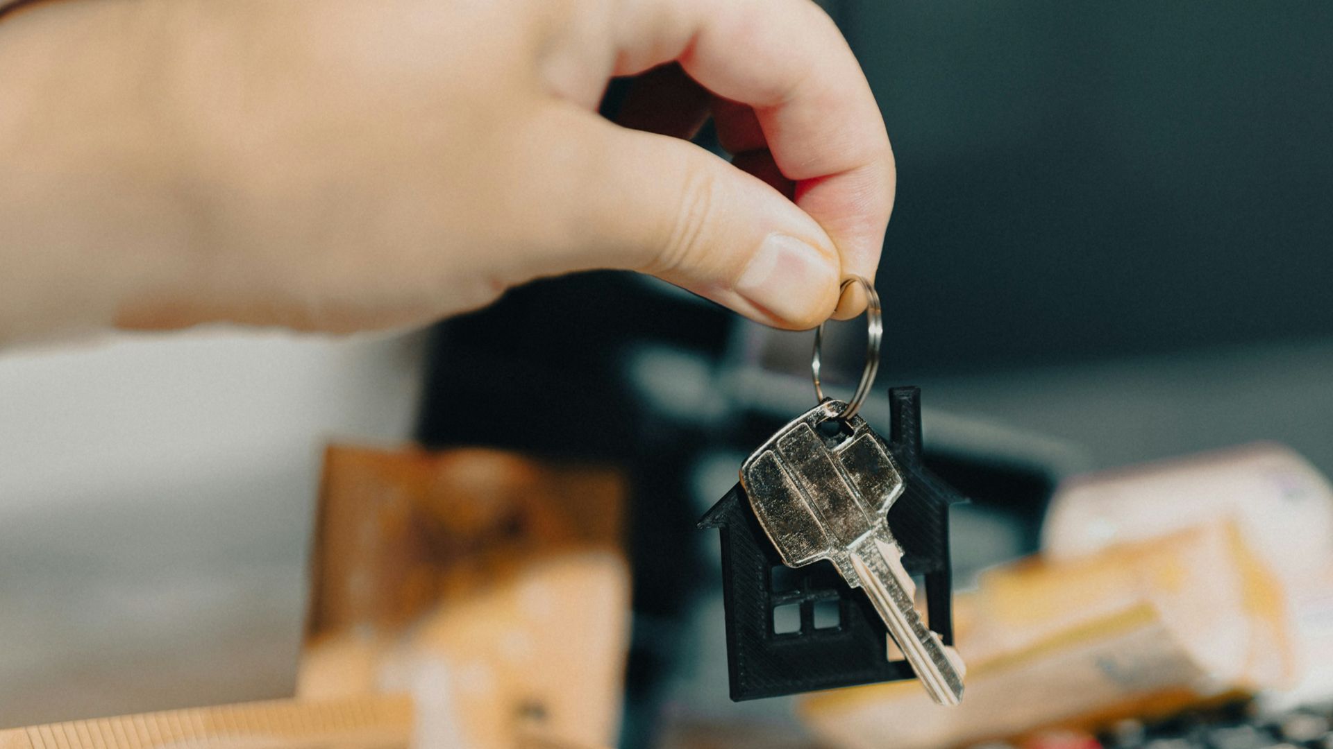 A person holding a house key in front of a calculator