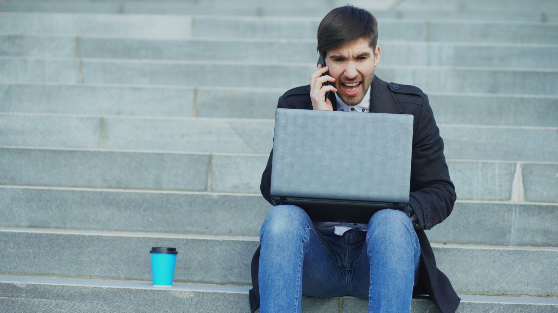 Man on phone with laptop on stairs