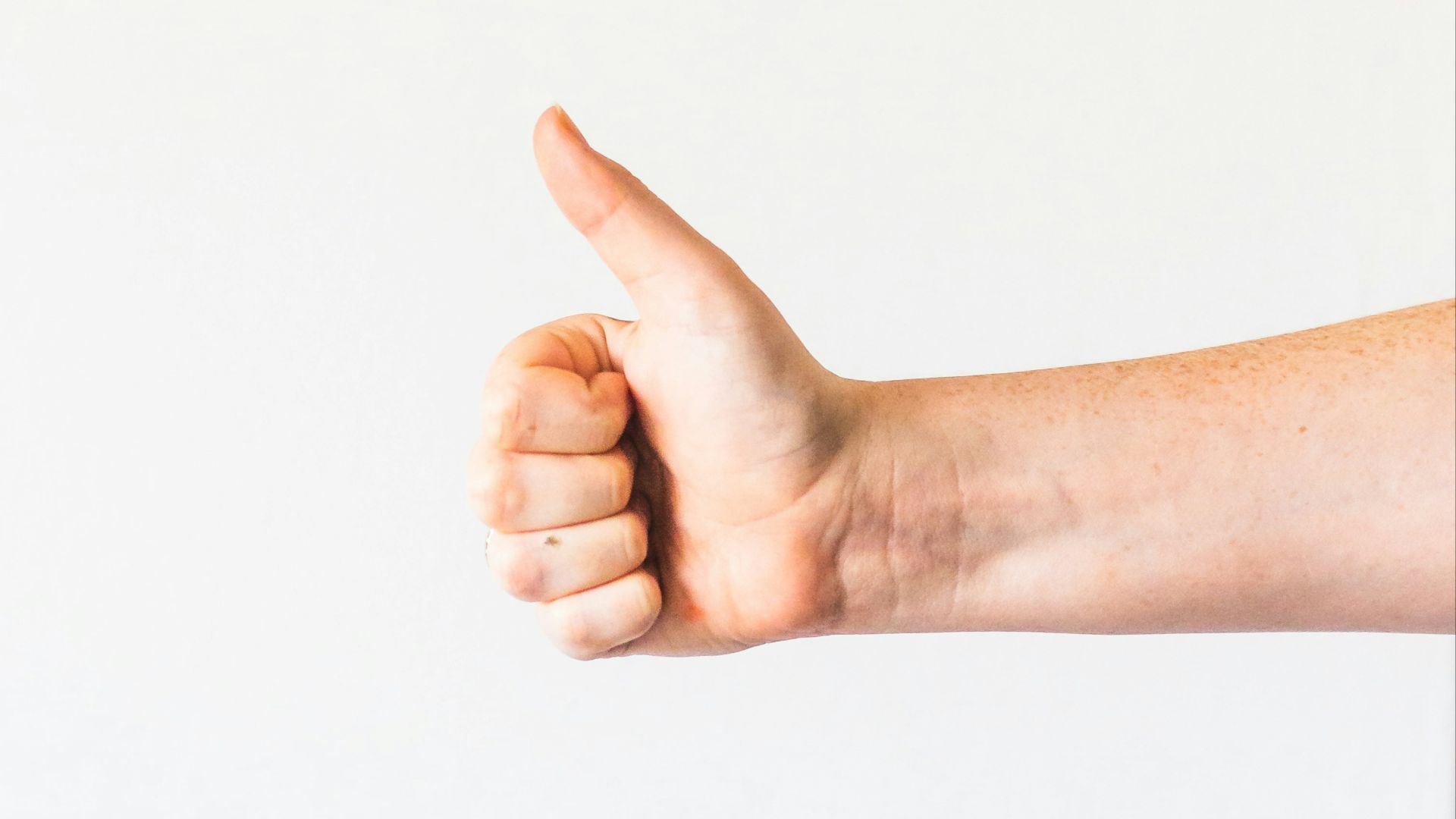 persons right hand doing thumbs up