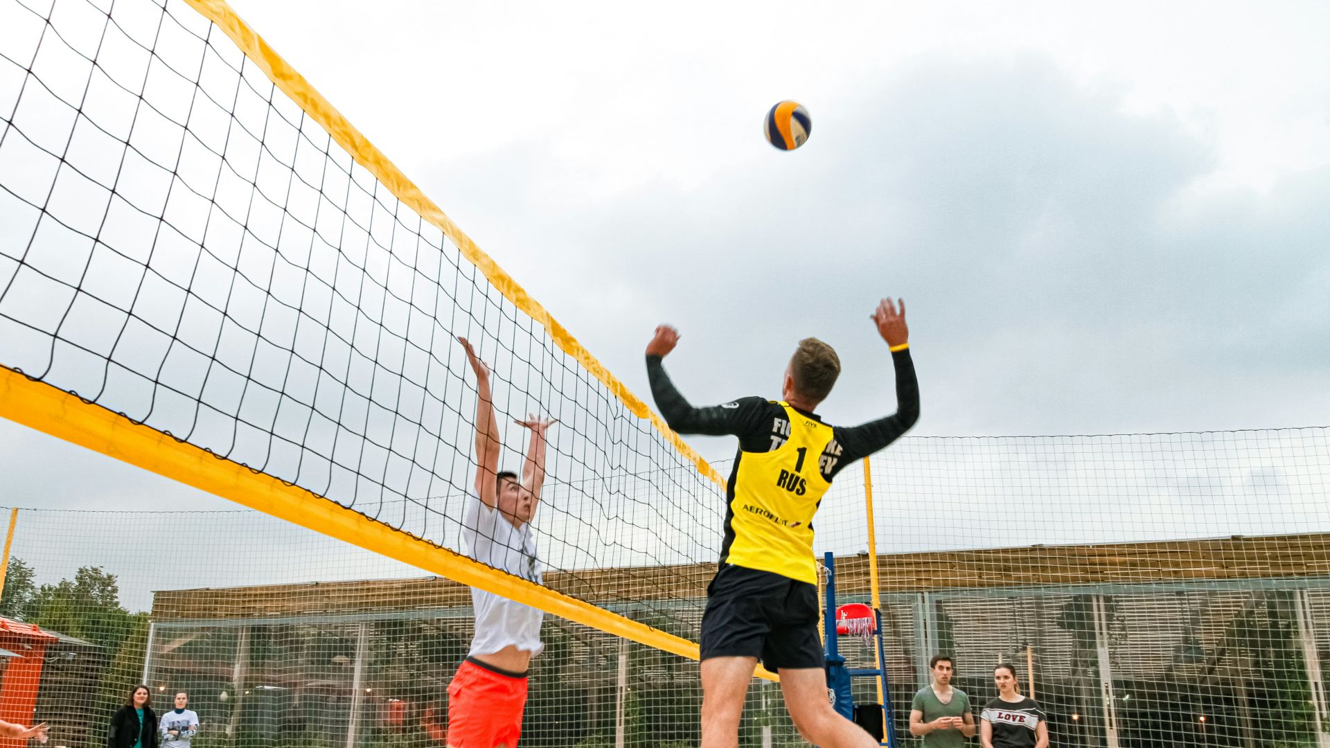 man wearing yellow and black long-sleeved shirt playing volleyball