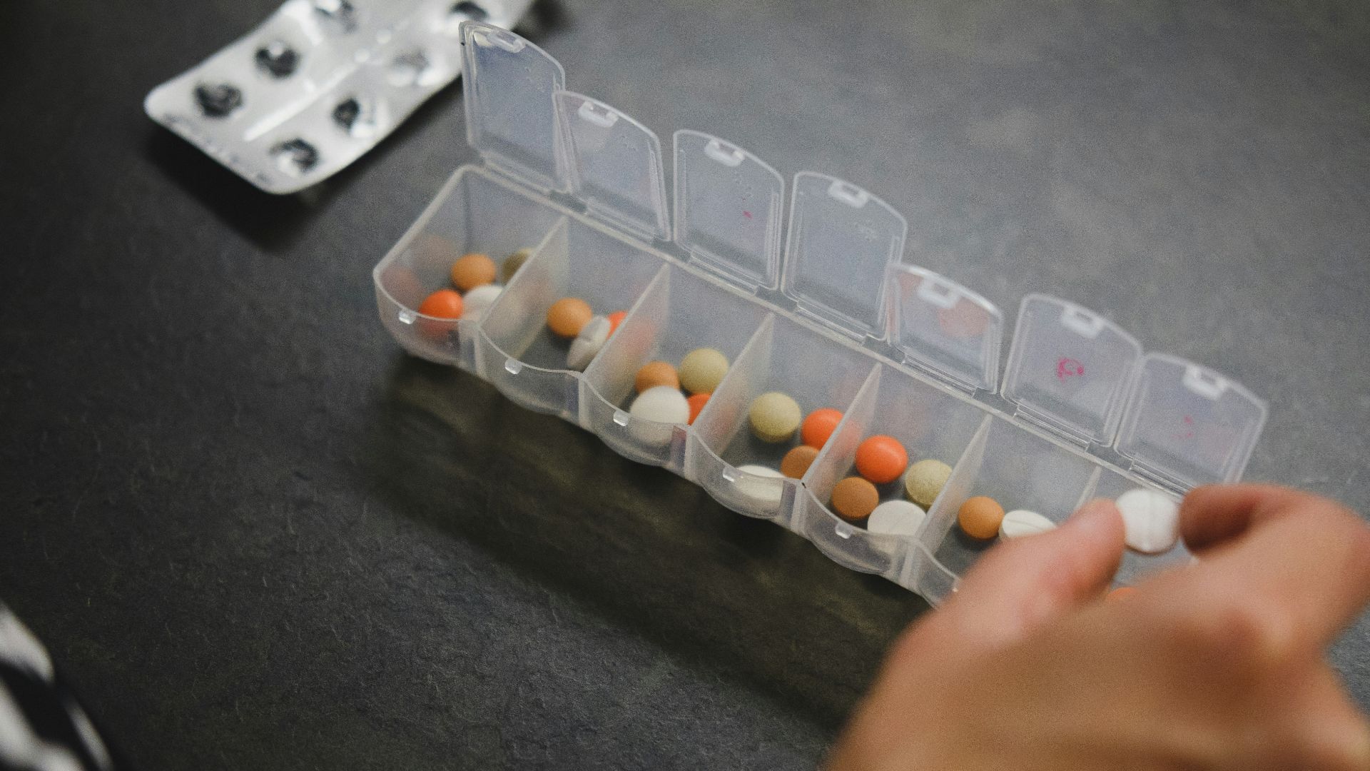 person about to pick medicine from medicine organizer