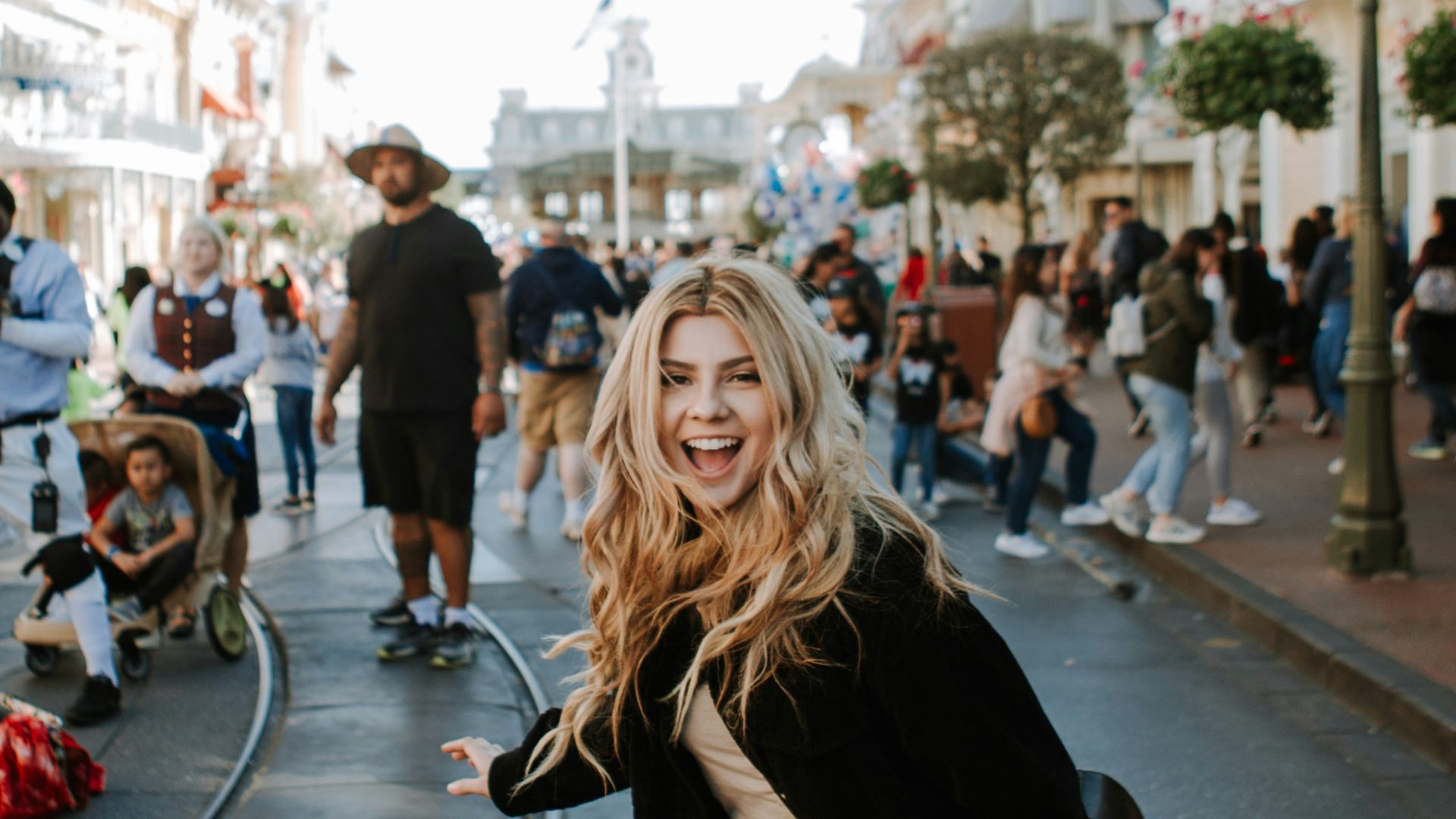 woman in black jacket and brown pants standing on sidewalk during daytime