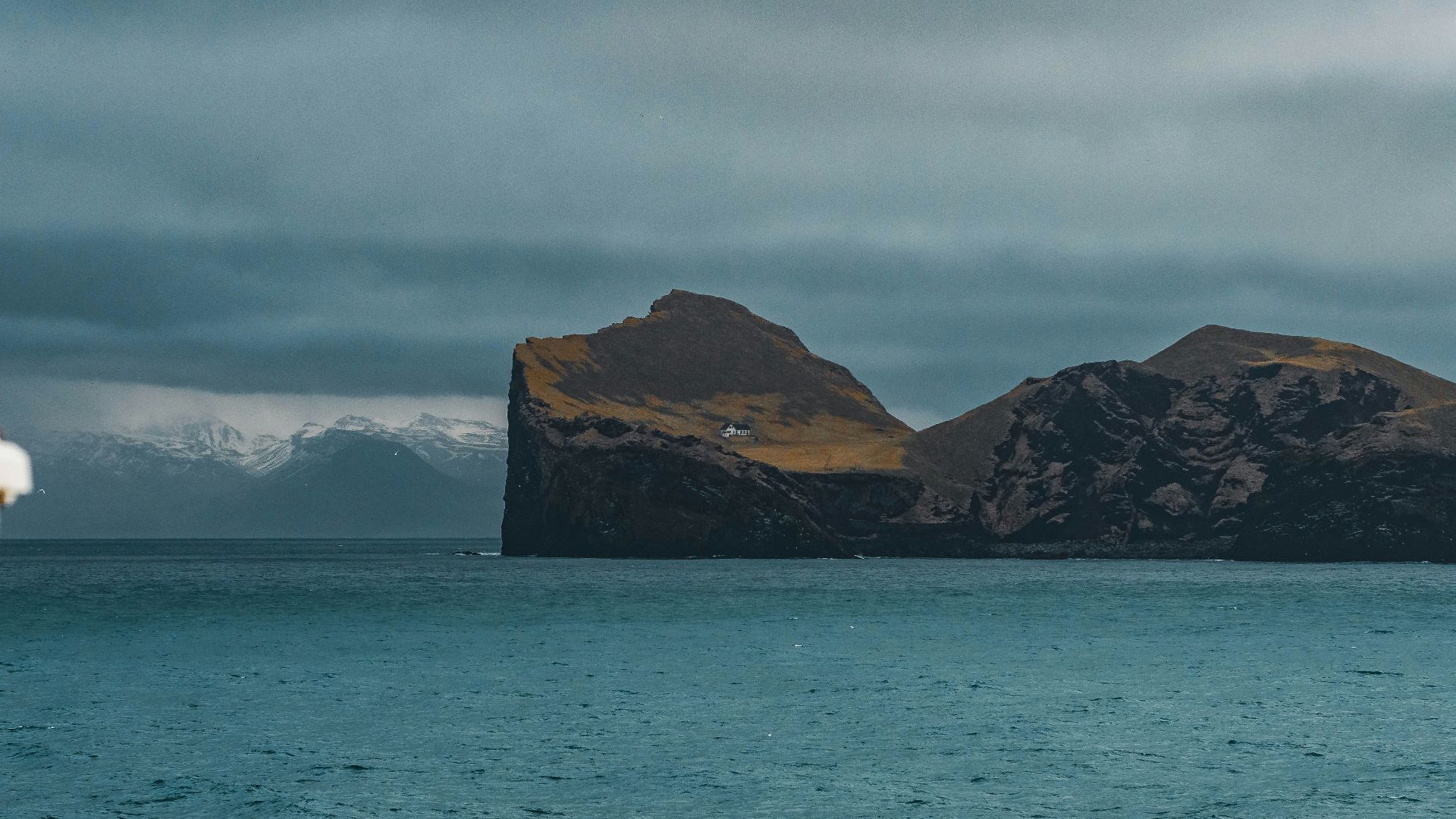 A rocky island sits in the vast, blue sea.