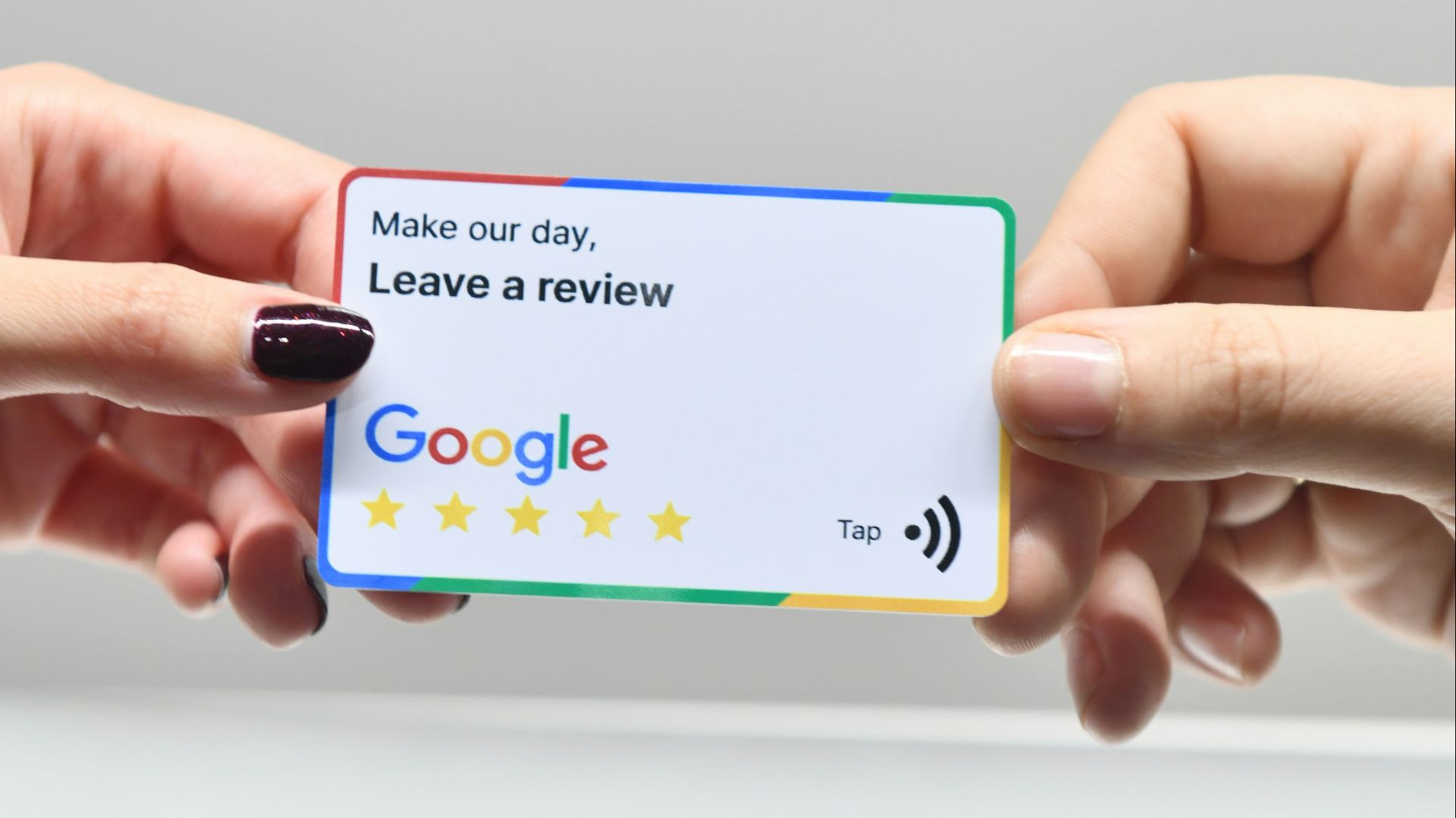 two hands holding a google credit card in front of an apple logo