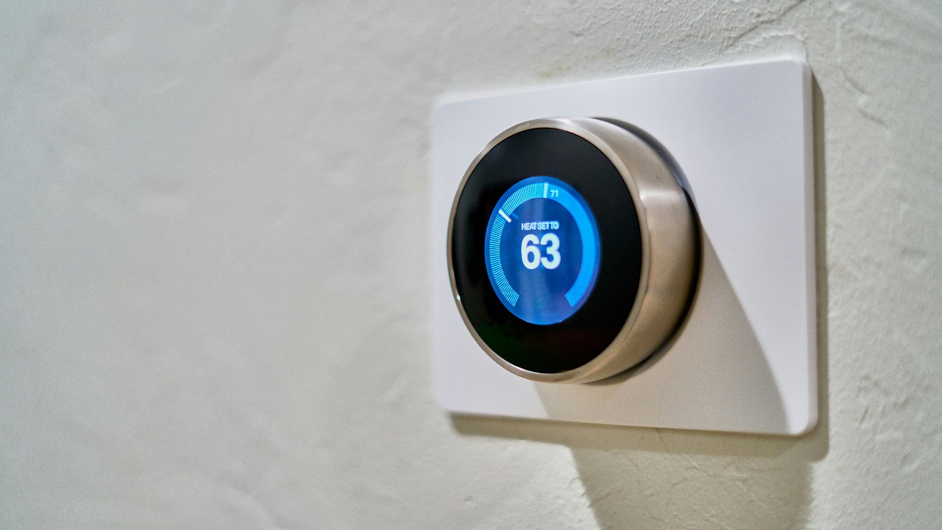 gray Nest thermostat displaying at 63