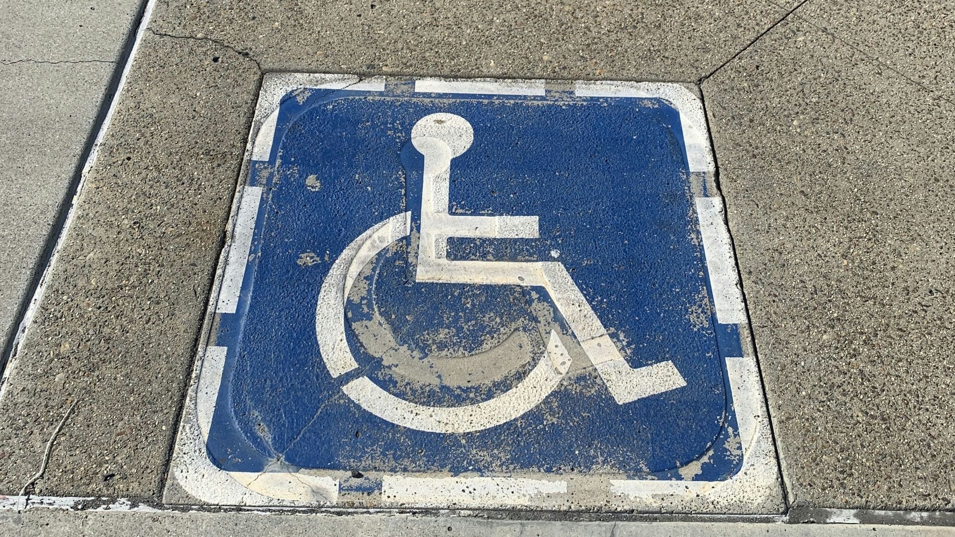 a handicap sign on the sidewalk of a city street