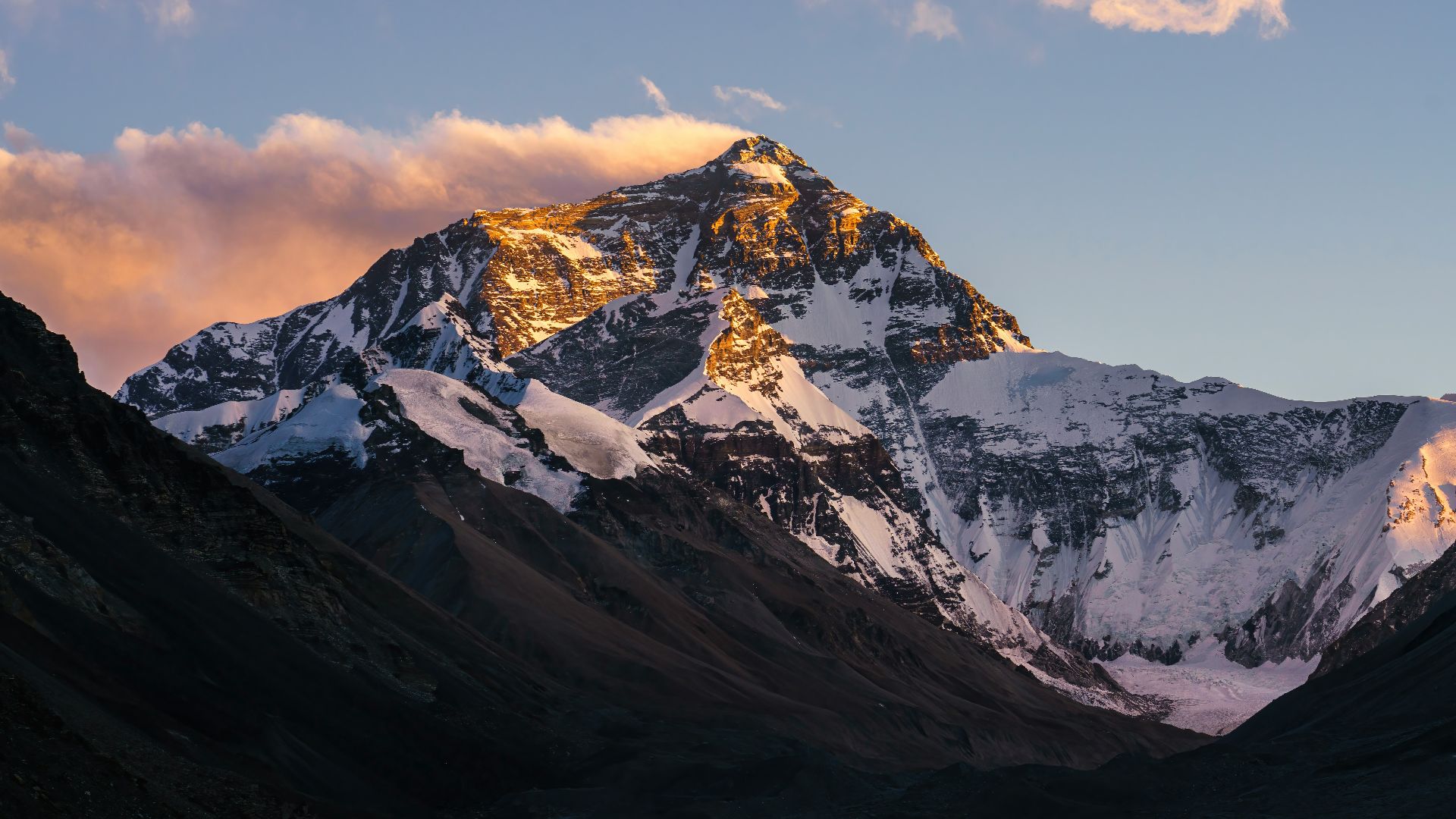 a snow covered mountain with clouds in the sky