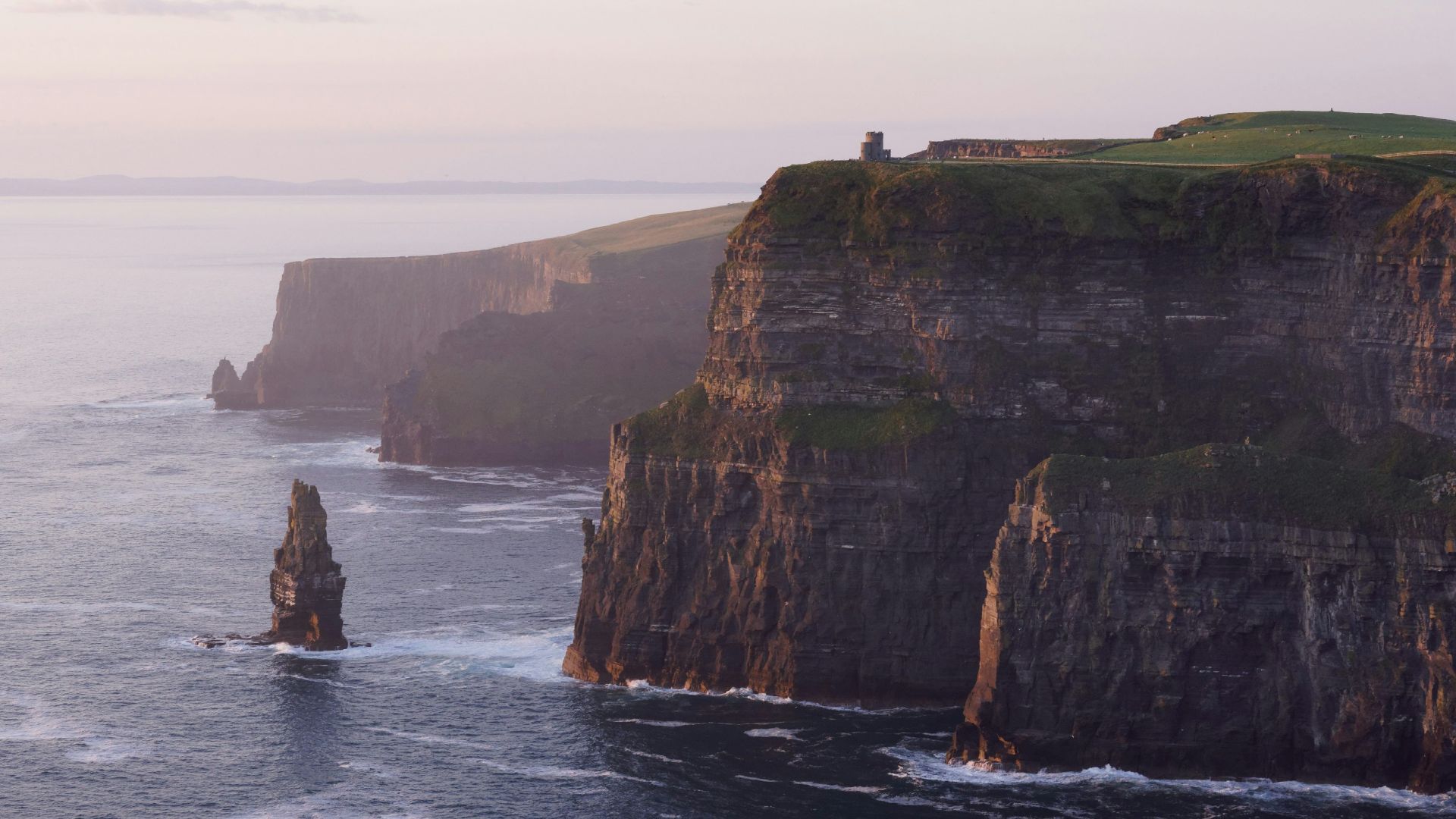 rock formation near sea under white sky