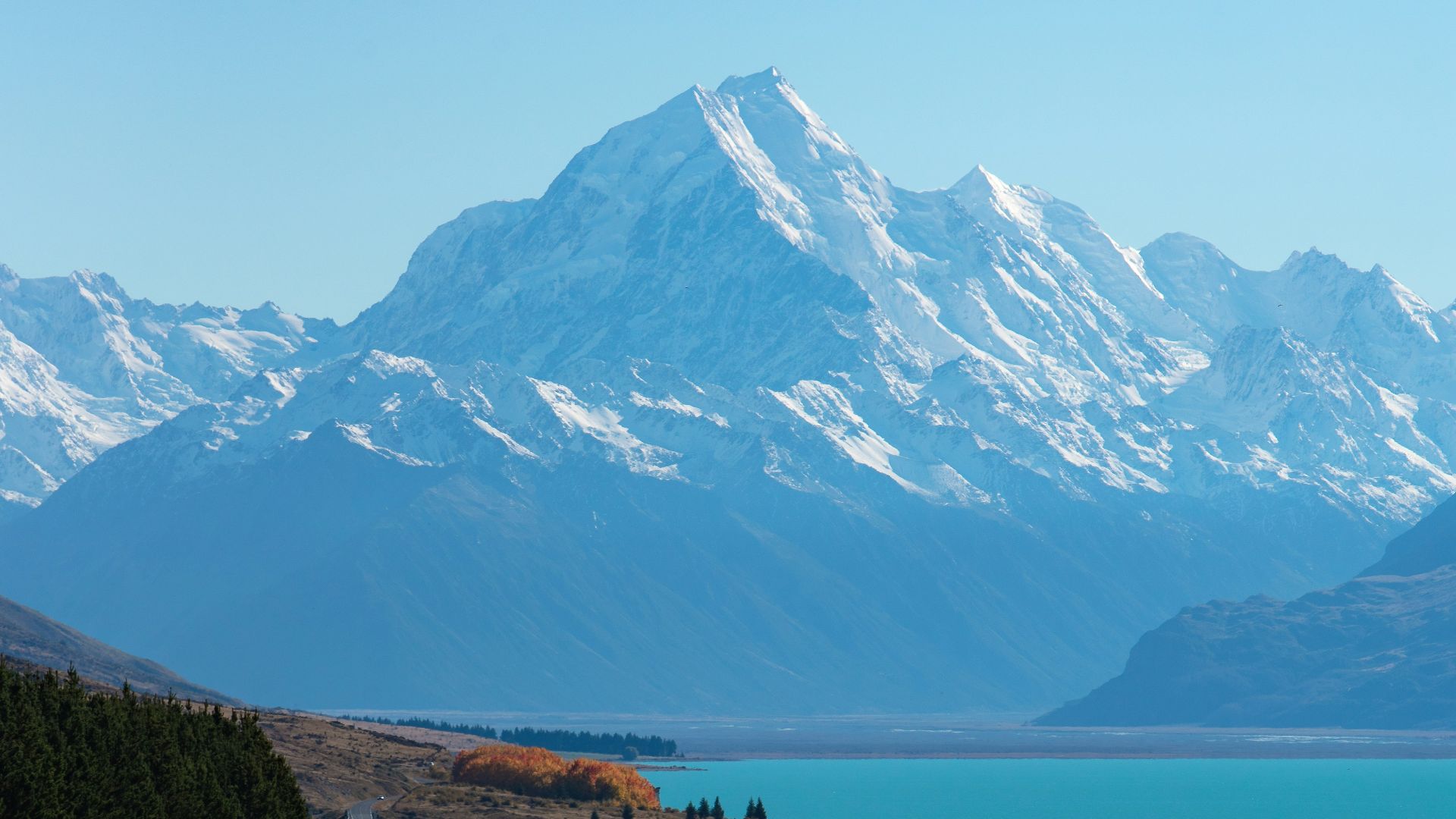 snow covered mountain near body of water during daytime