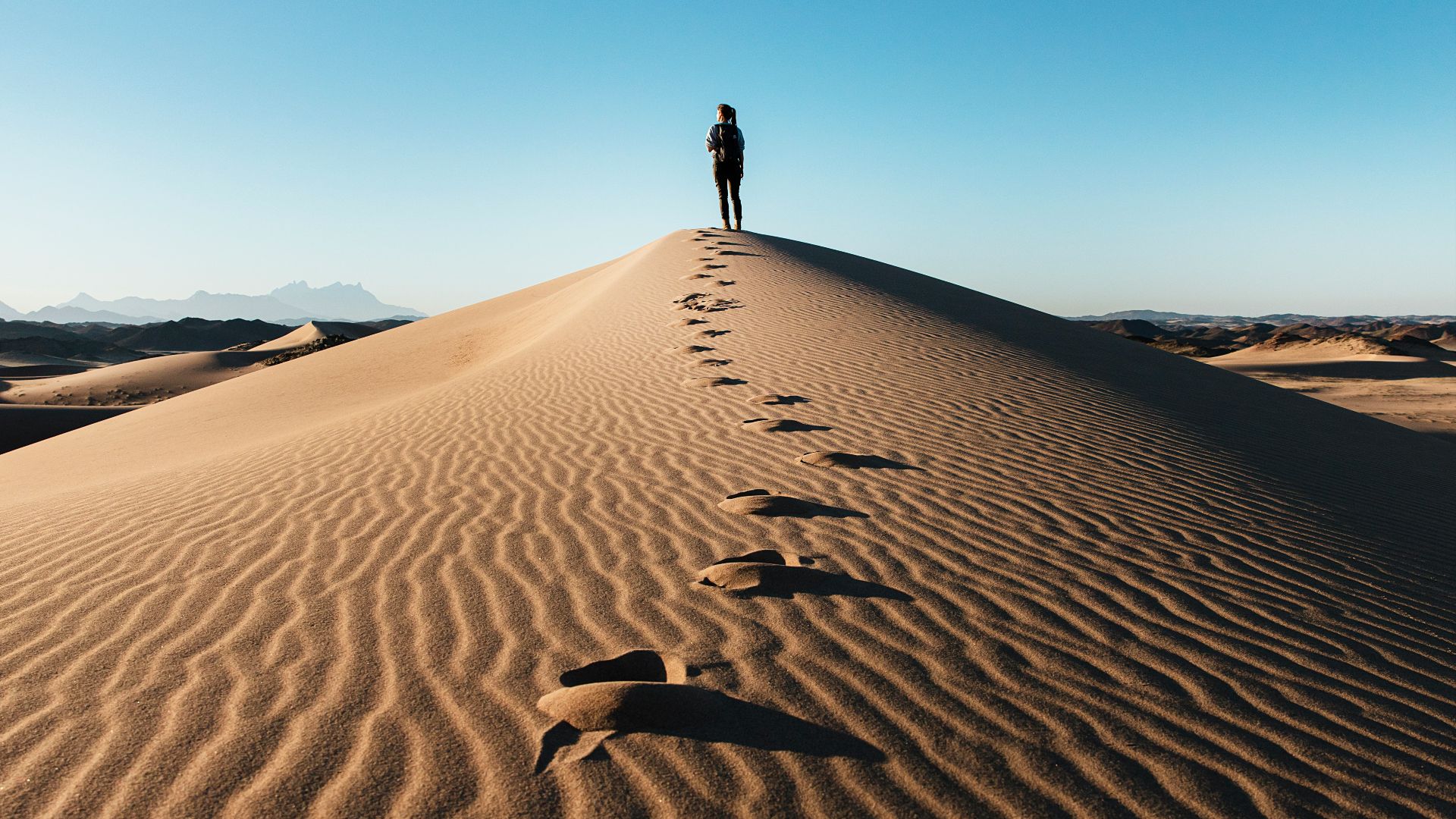 a person standing on top of a sand dune