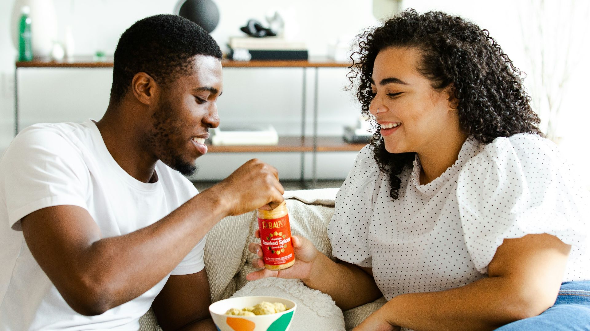 man in white crew neck t-shirt and blue denim jeans sitting on white sofa chair