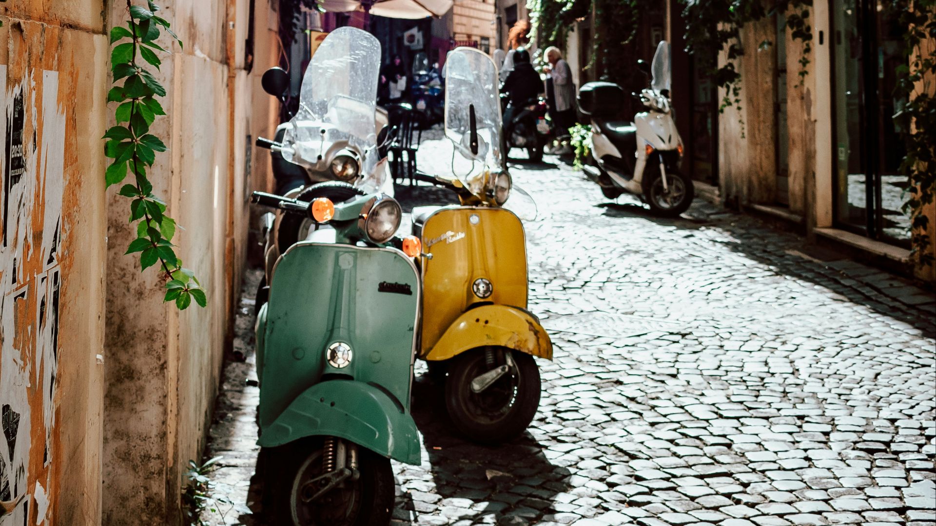 yellow and black motor scooter parked beside brown concrete building during daytime