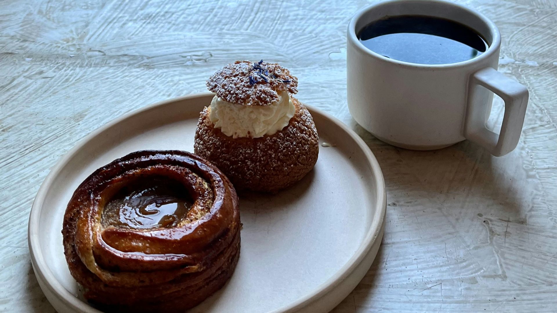 Coffee and pastries on a windowsill overlooking a courtyard.