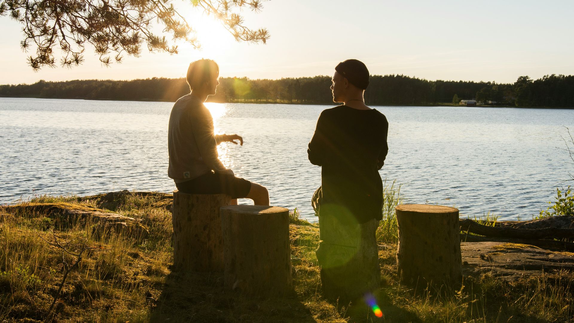 man in black jacket standing beside body of water during sunset