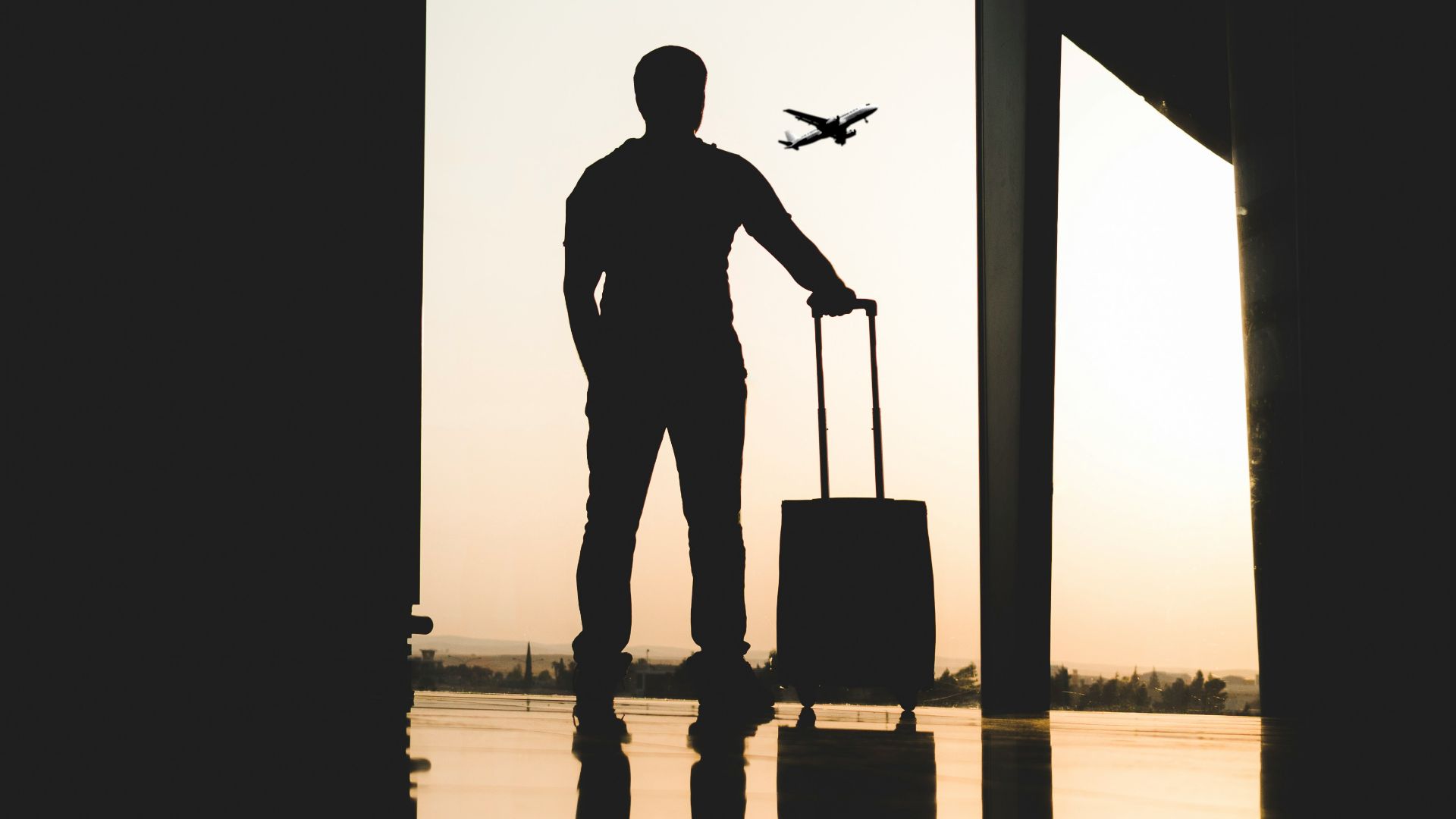 silhouette of man holding luggage inside airport