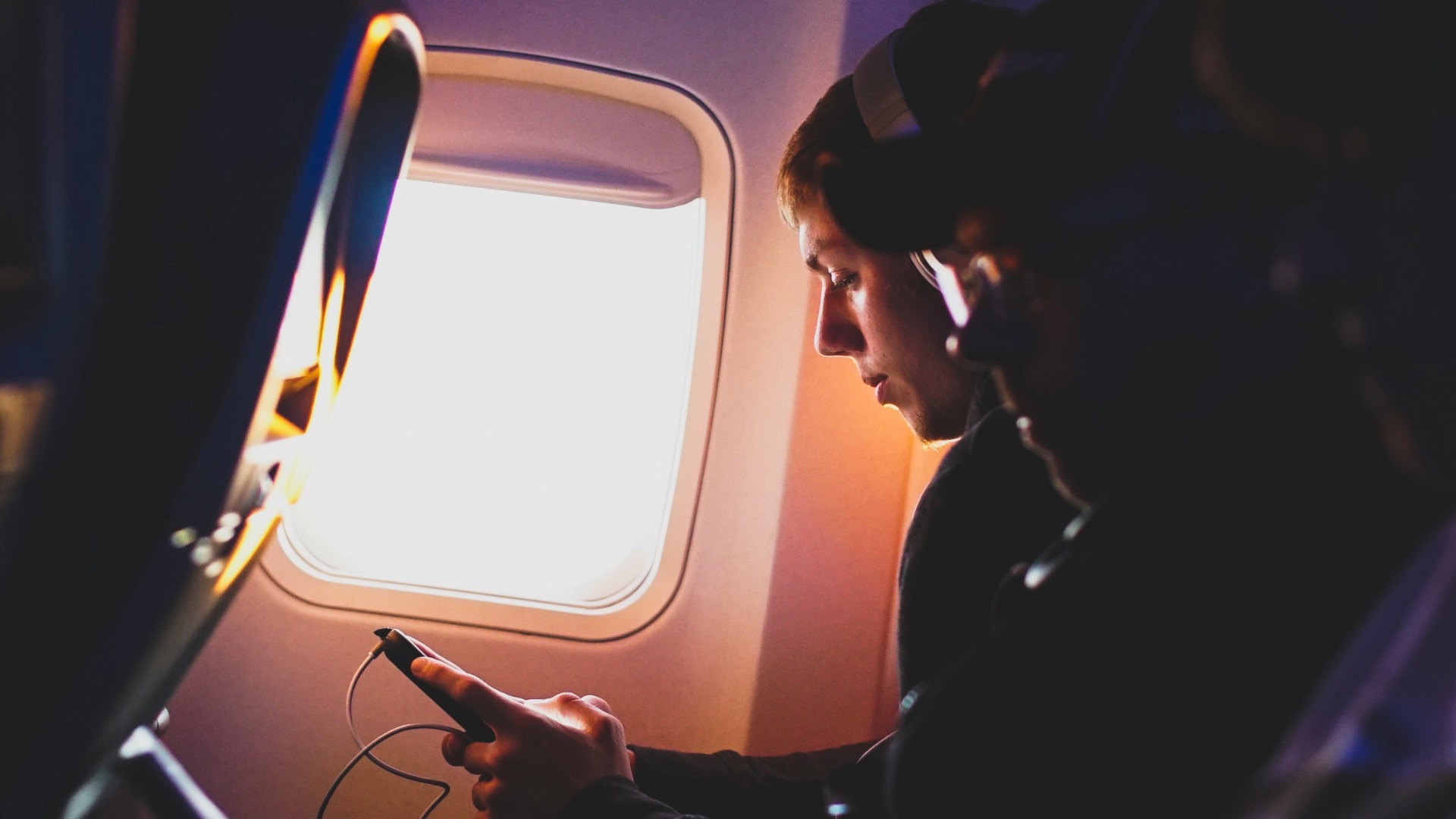 photo of three people listening to music inside airplane