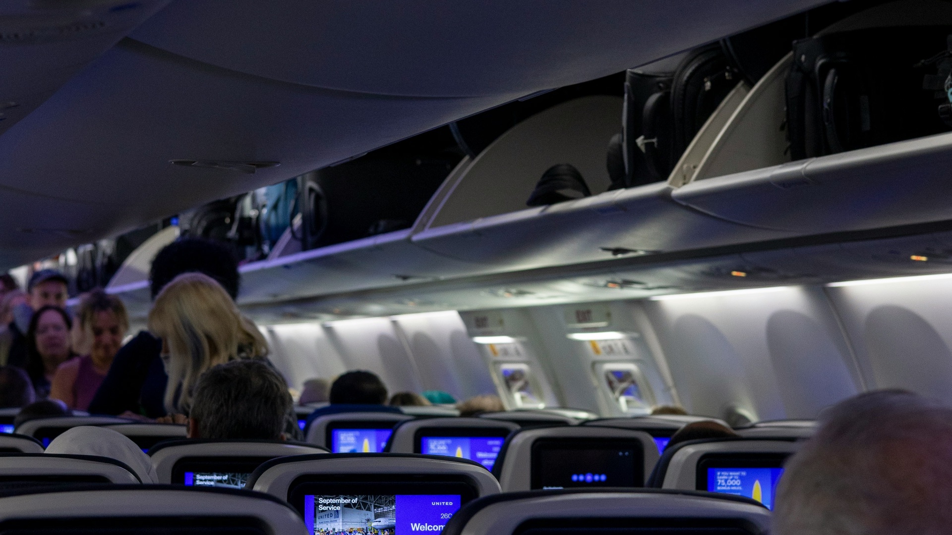 Interior view of airplane cabin with passengers and screens
