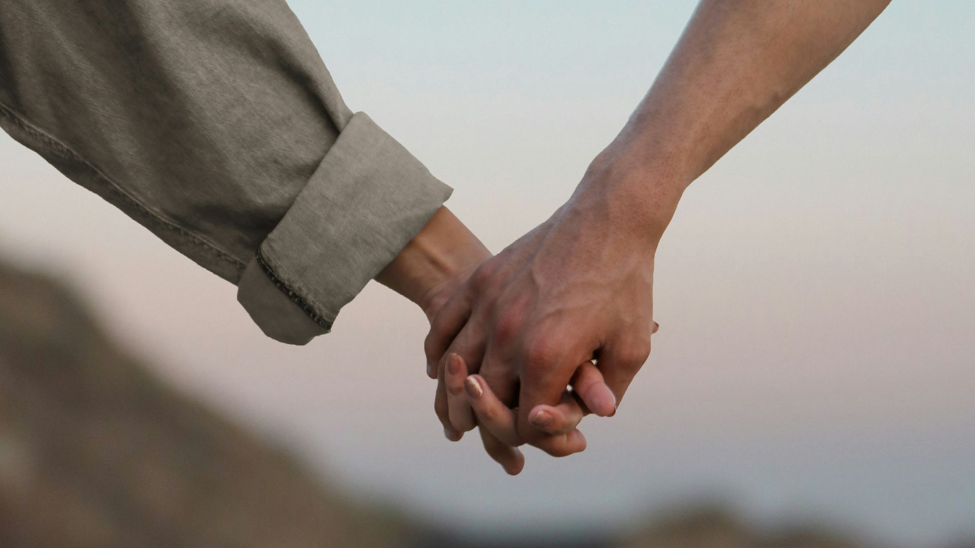 person in gray long sleeve shirt holding hands