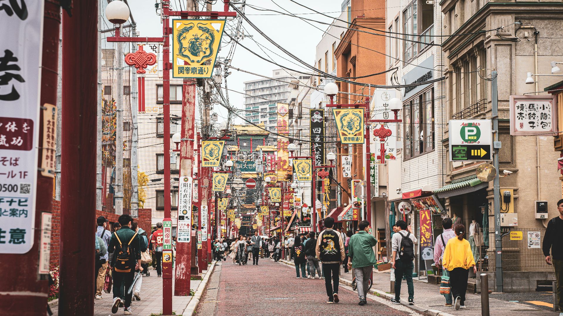 A group of people walking down a street next to tall buildings