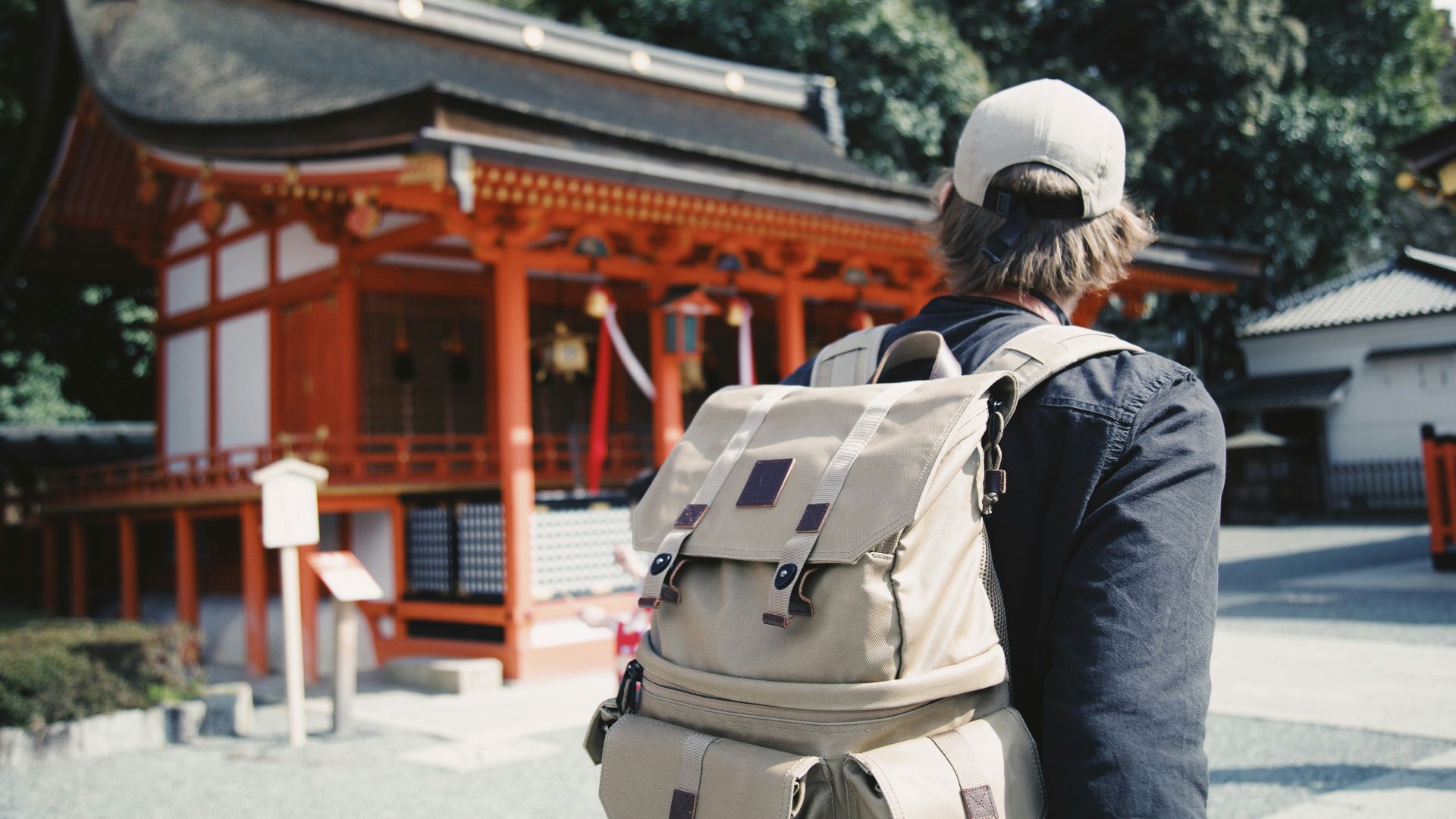 man wearing black top and backpack near orange structure