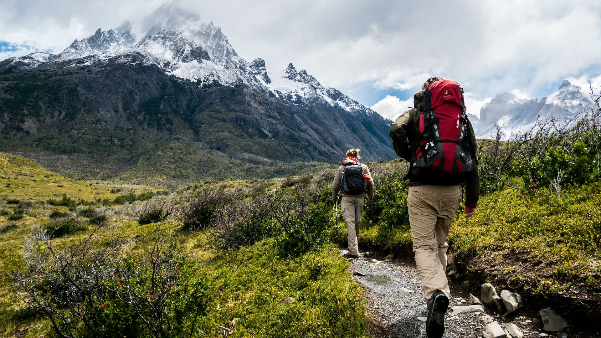 two person walking towards mountain covered with snow